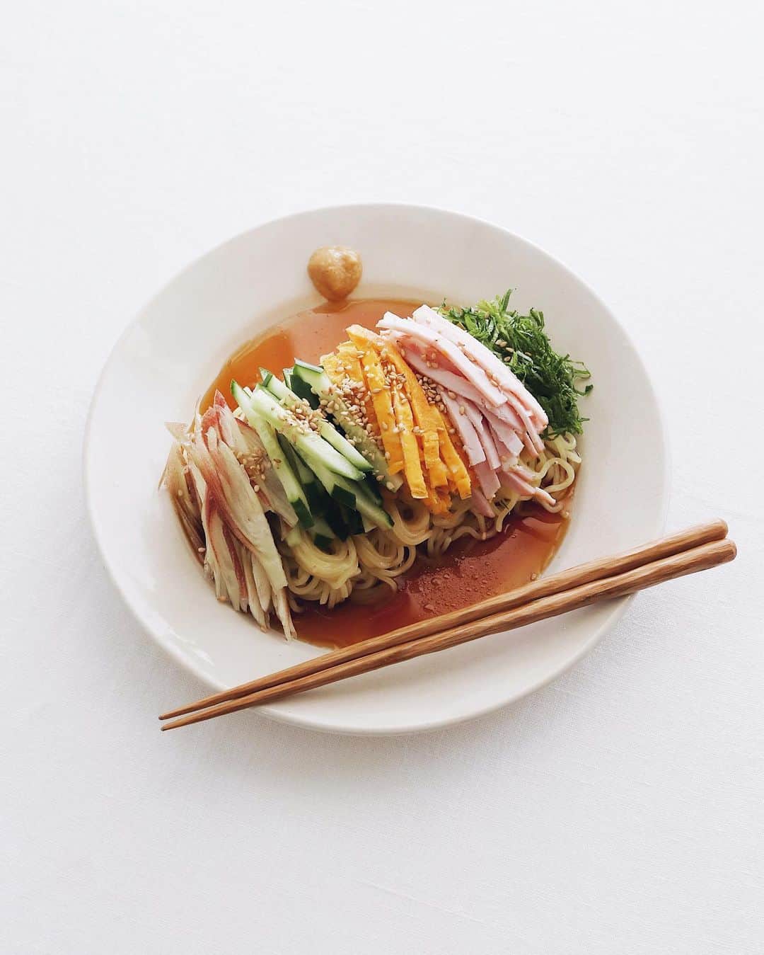 樋口正樹のインスタグラム：「hiyashi chuka . お昼にひとり冷やし中華。 タレは酸っぱめの甘酢で、 具材は大葉、ロースハム、 錦糸卵、きゅうり、茗荷。 . ここ数年ずっと盛り付け こんな感じに麺も具材も 平行的にお行儀を整えて ますが、食べるとなると よーくまぜまぜしてます。 それはもう見た目が酷く 美味しくても載せれない😅 . . #冷やし中華 #ひとりごはん #hiyashichuka #coldchinesenoodles」