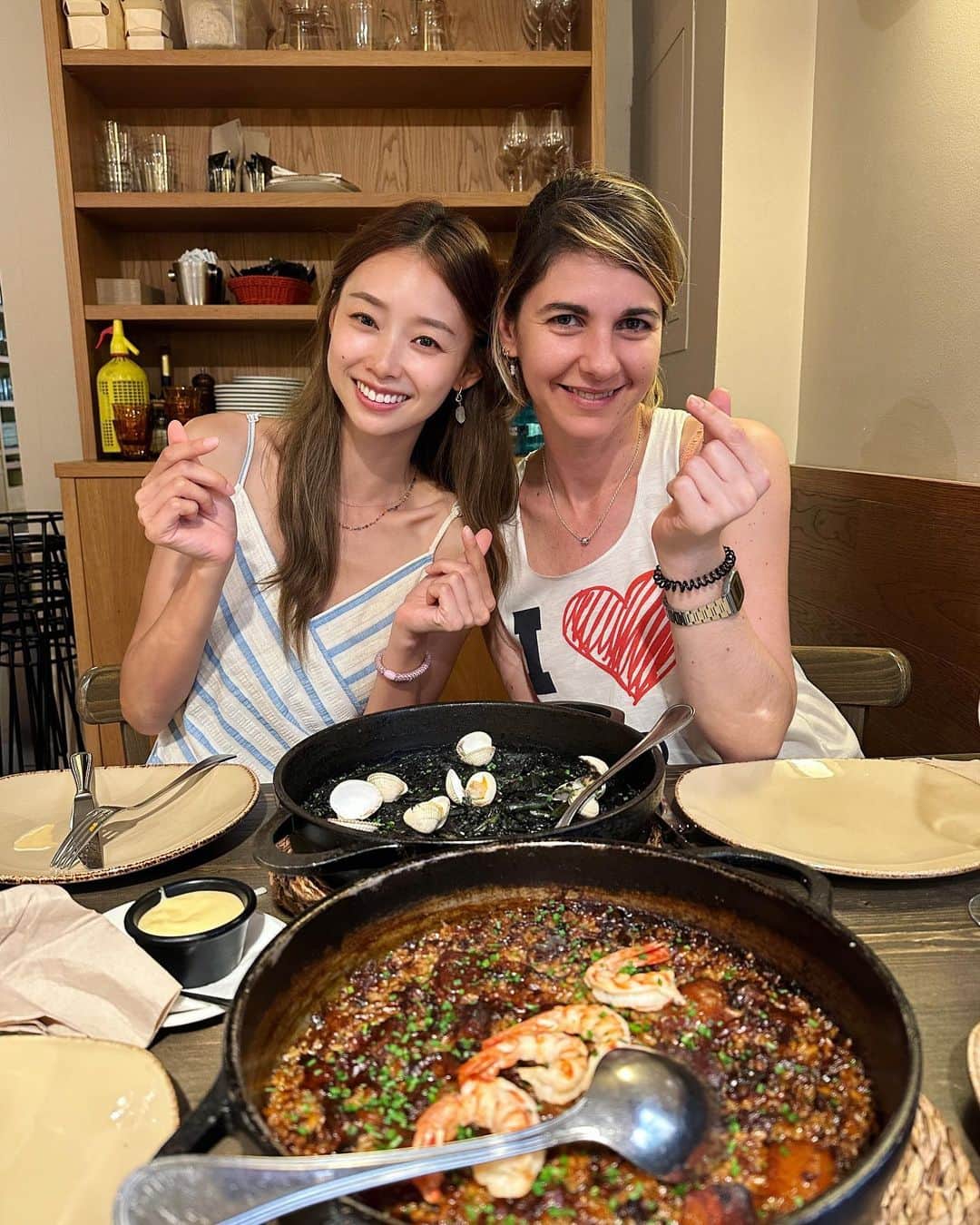 吳斐莉のインスタグラム：「巴塞隆納的海鮮飯，請收🙌🏿  我必須說，最好吃的海鮮飯已經在我們家了，但吃不到的你們可以去吃這家😆西班牙朋友推薦的～  要謹記 海鮮飯菜單上都是寫一人份價格 但最少一定要點2人份 2個人吃一鍋其實就滿多的 如果可以四個人吃最好 還可以點2個口味  我們是點黑飯跟一個蝦蝦牛肉口味的 對！海鮮飯可不止海鮮 也是有肉口味的喔😎(各種肉) 我跟老公一致覺得 牛肉口味吃起來超像台灣控肉飯🤣 還懷疑裡面是不是有加醬油 真的太太太像了！  這家很熱門要先訂位 那兩盤前菜也都很推薦🤤  圖二是盯著出菜口的兩個男子🤣」
