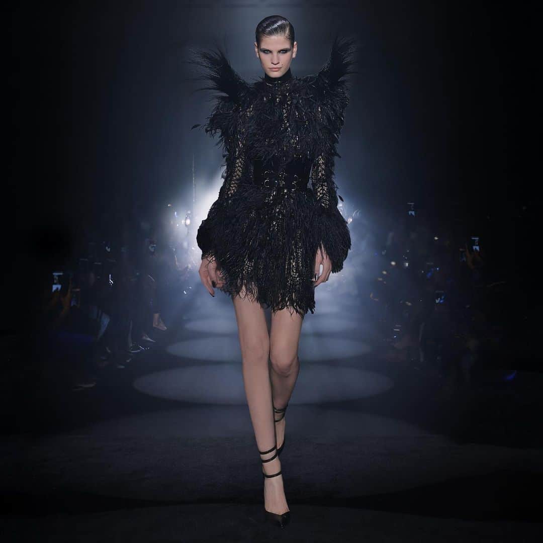 ジュリアンマクドナルドのインスタグラム：「Possessing a mesmerizing elegance, the alluring @kateryna.lashko graces the catwalk in a JULIEN MACDONALD signature couture knit feather minidress, embellished with intricate handsewn jet black Japanese micro cutdana beads and ball chain fringes over a handtooled knit lace base with an intarsia of faceted jet Swarovski crystals.   Finished with signature statement shoulders covered in handsewn stripped feathers and worn with a couture Super Cinch Waist Belt by none other than @jivomir.domoustchiev  Feather work by @victoriagrant  Big thank you to all who contributed to a successful JxG AW24 show  Styling: @karlplewka Makeup: @wendyrowe Hair: @sammcknight1 Nails: @glitterbels Shoes: @charkviani Belts: @jivomir.domoustchiev Tanning: @cocoandeve Production: @mybeautifulcity Movement Direction: @officialroyston  Music: @djsmokinjo Casting: @angusctmunro PR: @purplepr Official Sponsor: @weshopsocial」