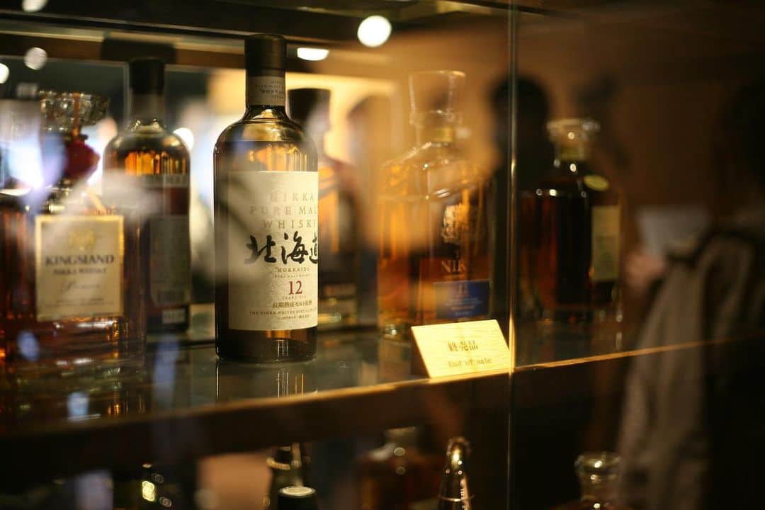 職人.comさんのインスタグラム写真 - (職人.comInstagram)「【ニッカウヰスキー余市蒸溜所】  日本のウイスキー界では「伝説」とも言える、ニッカウヰスキーの創業者・竹鶴政孝。日本のウイスキーの父とされる竹鶴は、「日本人に本物のウイスキーを飲んでもらいたい」というその思いと情熱を生涯にわたって抱き続け、人生のすべてをウイスキーづくりに捧げた人物です。2014年9月～2015年3月に放送されたNHKの連続テレビ小説『マッサン』のモデルになった人物としても記憶に新しいでしょう。   彼は日本で初となる本格的なウイスキーの製造という夢を叶えるため、大正時代にウイスキー誕生の地であるスコットランドへと渡り、本格的なウイスキーの製造技術を持ち帰りました。のちに英国首相となるヒューム氏をして「わがスコットランドに40年前、頭の良い日本の青年がやってきて、1本の万年筆とノートで英国のドル箱であるウイスキーづくりの秘密を盗んでいった」と、ユーモアたっぷりに称賛されたのだそうです。そしてウイスキーづくりを知っているただ一人の日本人として、サントリー株式会社の前身である寿屋・鳥井信治郎に招かれ、山崎蒸溜所の建設に深く関わった竹鶴は、自ら工場長としてウイスキーづくりに没頭、ロングモーン蒸溜所での研修から10年の月日が流れた1929年に、ついに日本発の本格ウイスキーを世に送り出しました。   その竹鶴が日本中を探し回り、ついに見つけたのが北海道積丹半島にある余市。清らかな水が沸き、涼しい気候でありながら湿度も高いという、スコットランドによく似た気候の余市は、竹鶴が夢を託すための理想の土地そのものでした。1934年には、「大日本果汁株式会社」を設立し、工場敷地内に建設した木造洋風家屋に、スコットランドで出会い結婚した妻のリタを迎え入れます。しかし順風満帆には進まず、ウイスキーができるまでは時間がかかることと、設立直後で資金不足だったことを理由に、最初は林檎ジュースを作りながら資金を得、ウイスキーの原酒づくりをスタートします。スコットランド留学から22年目の1940年、ようやく完成した竹鶴のウイスキーは「大日本果汁株式会社」から「日」と「果」の文字を取り、「ニッカウヰスキー」と名付けられました。愚直なまでにまっすぐに歩んだこれまでのすべてが、角型の瓶に詰められた琥珀色の液体として目の前に現れた時、それは竹鶴と妻リタにとって、そしてウイスキーづくりに関わった技師たち全員にとって、至福という言葉では言い表せないほどの喜びだったに違いありません。   ニッカウヰスキー余市蒸溜所は、小樽ショールームのある小樽市の小樽駅前からバスで約45分。蒸溜所では無料のガイドツアー（要予約）が行われており、モルトウイスキーの製法や製造工程の説明を受けながら見学することができます。私たちがガイドツアーに参加した日の余市の天候は雨。その天気が作り出す空気は、まさに竹鶴がスコットランドで体験した「冷涼湿潤」そのものなのではないかと思うほど。雨と霧で霞がかった蒸溜所の広大な敷地には、まるでスコットランドにあるかのような建物が並び、別世界のような風景が広がっていました。   余市蒸溜所では、現在でも伝統的な石炭直火蒸溜により、重厚で力強いモルトウイスキーが生産されています。ガス燃料が主流となった今日、石炭を使用し、ポットスチルを直火炊きして蒸溜する蒸溜所は、本場スコットランドでも数えるほどしかないそうです。その開かれた扉から見える真っ赤に燃えた石炭と炎、吹き付ける熱風に、創業以来受け継がれてきた技術、精神、伝統、そして「本物」を作り続けるという信念を感じずにはいられませんでした。   小樽から日帰りで行ける、ウイスキーづくりの理想郷・余市。世界中の多くのウイスキーファンを魅了してやまないニッカウヰスキーの歴史に触れ、先人の偉業と、今も受け継がれる伝統を感じてみてはいかがでしょうか？   ニッカウヰスキー余市蒸溜所 https://www.nikka.com/distilleries/yoichi/  小樽ショールーム https://www.shokunin.com/jp/showroom/otaru.html   参考資料 https://www.town.yoichi.hokkaido.jp/machi/yoichistory/2014/sono115.html https://ja.wikipedia.org/wiki/%E7%AB%B9%E9%B6%B4%E6%94%BF%E5%AD%9D  @shokunincom  #職人ドットコム #ニッカウヰスキー #余市蒸溜所 #ニッカウヰスキー余市蒸溜所 #ニッカウイスキー #余市 #ニッカウィスキー #ニッカウィスキー余市蒸留所 #ニッカウィスキー余市蒸溜所 #ニッカウィスキー工場 #ニッカウイスキー余市蒸溜所 #ニッカウイスキー工場 #ニッカウイスキー余市 #竹鶴政孝 #日本のウイスキーの父 #ウイスキーづくり #ウイスキー作り #ウイスキー工場 #ウイスキー工場見学 #ニッカウヰスキー株式会社 #ニッカウヰスキー蒸留所 #ニッカウヰスキー工場 #余市郡 #よいち #ヨイチ #ニッカ」6月18日 13時28分 - shokunincom