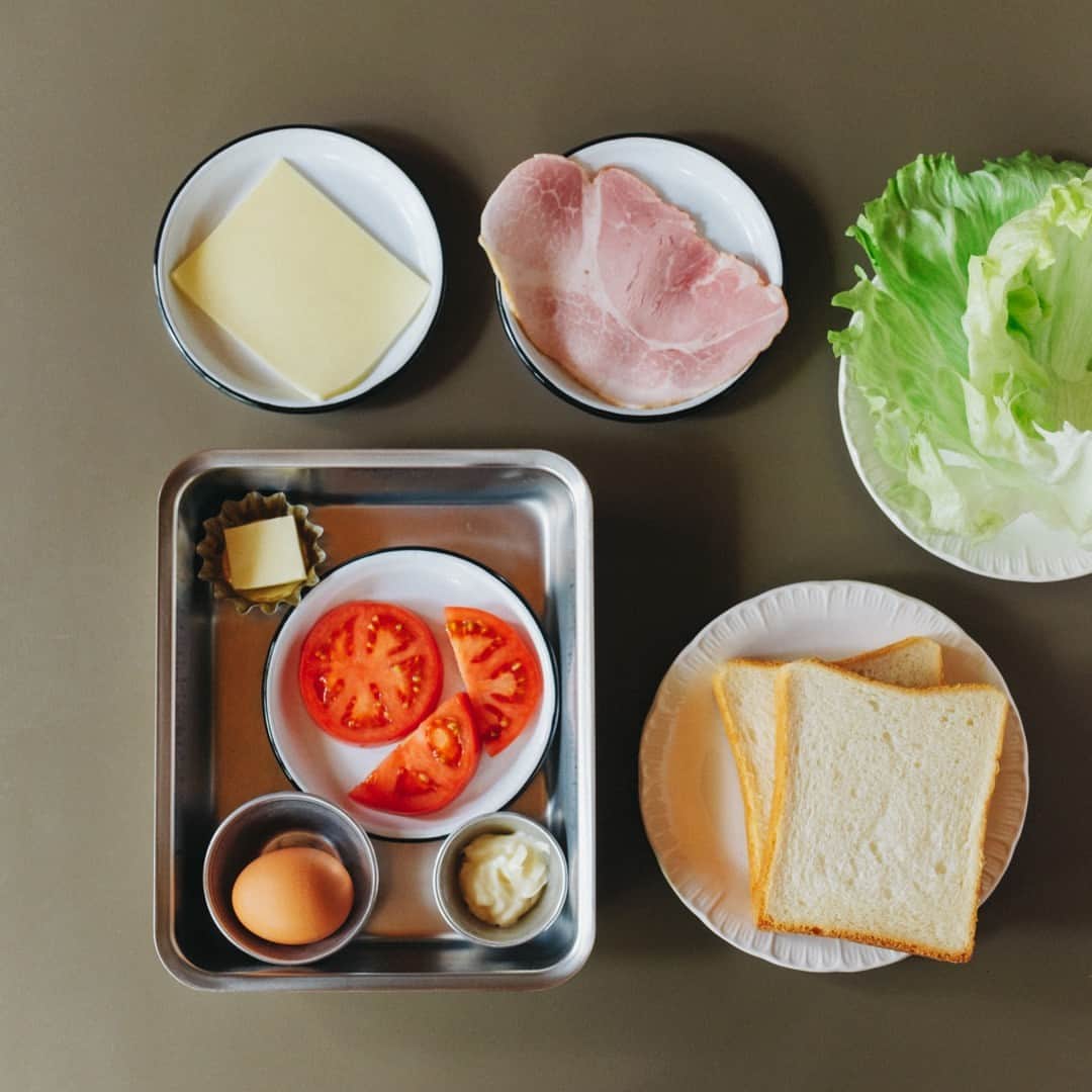 北欧、暮らしの道具店さんのインスタグラム写真 - (北欧、暮らしの道具店Instagram)「おいしさの秘密は重ねる順番。 とろっと卵とチーズが嬉しい「定番サンドイッチ」 . - - - - - - - - - - - - - - - - - 思わずごきげんになってしまう サンドイッチレシピを教えてくださるのは、 料理家の小堀紀代美（こぼり きよみ）さんです。  家にある材料ですぐできる、 定番のサンドイッチをご紹介します。 . - - - - - - - - - - - - - - - - - いちばんシンプル、いちばんおいしい。 小堀さん家の定番朝サンド - - - - - - - - - - - - - - - - -  【材料（2つ分）】 食パン…2枚（6枚切り） レタス…2〜3枚 ハム…1枚 チーズ…1枚 トマト…2枚（1cmほどの輪切りで） 卵…1個 バター…10g マヨネーズ…大さじ1  ※今回のレシピではももハムとゴーダチーズを 使用していますが、スライスチーズなど お好みの種類でOKです  【下準備】 レタスはほんの少しの塩（分量外）をふって 食パンの大きさよりやや小さめに 折りたたんでおく。  【作り方】 ❶食パンはトーストして、 両面の内側にマヨネーズをぬる。  ❷スクランブルエッグを作る。 卵をボウルに溶きほぐし、 塩少々（分量外）を入れてよく混ぜる。 フライパンにバターを入れて 強めの中火にかけ、バターが溶けたら 卵液を入れる。 ゴムベラで大きくまとめて 半熟のうちに取り出す。  ❸パン、トマト、ハム、チーズ、 スクランブルエッグ、レタス、パンの順に 重ねたら、上からぎゅっと押して馴染ませる。  ❹大きめにカットしたクッキングシートの 中央にサンドイッチを置く。 シートの上下の端をあわせて、 1cm幅で折りたたんでいく。 左右の端は上から押さえながら三角形に折り、 底面のほうに折り曲げる。 半分にカットしたら完成。 . - - - - - - - - - - - - - - - - - ■ 小堀さん  「サンドイッチをべちゃっとさせずに おいしく作るコツは、 パンの内側にバターやマヨネーズなどの油脂を しっかり塗ること。  それから、重ねる順番も大切です。 今回だと、チーズの上に 温かいスクランブルエッグをのせることで とろっとした食感が楽しめます。 ハムやチーズの塩気でレタスを食べたいときは、 それらを隣どうしにするのもいいです。  色々試して、おいしい重ね方を 見つけてみてくださいね」 . - - - - - - - - - - - - - - - - - . #kitchen#kitchendesign#kitchenware#food#foodstagram #サンドイッチ#レシピ#サンドイッチレシピ#お弁当#ランチ#お昼ご飯#夜ご飯#今日のごはん#小堀紀代美 さん#家じかん#料理#キッチン#キッチン雑貨#シンプル#シンプルライフ#シンプルデザイン#暮らしを楽しむ#日々の暮らし#北欧#暮らし#北欧暮らしの道具店」6月21日 17時03分 - hokuoh_kurashi