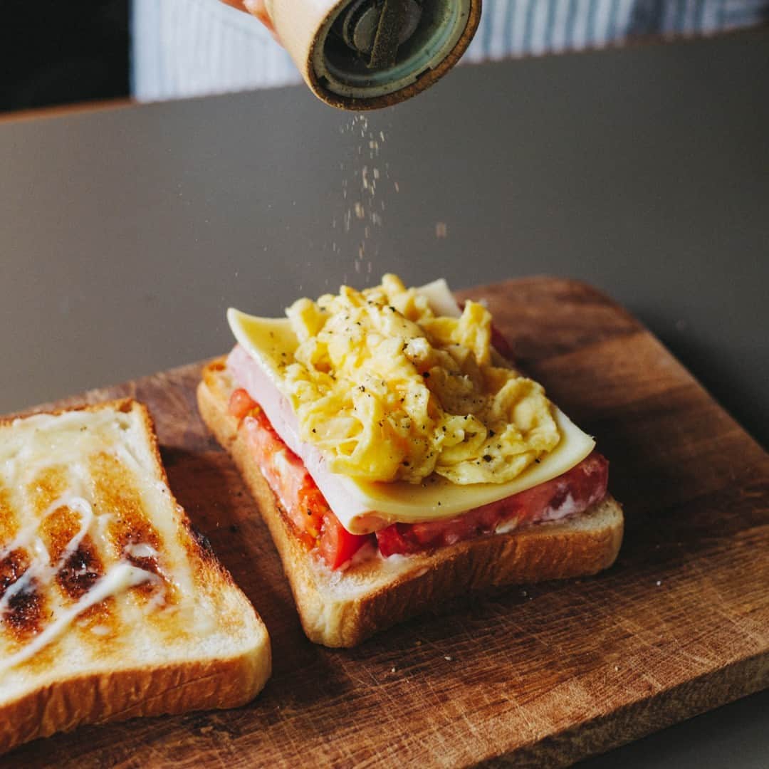 北欧、暮らしの道具店さんのインスタグラム写真 - (北欧、暮らしの道具店Instagram)「おいしさの秘密は重ねる順番。 とろっと卵とチーズが嬉しい「定番サンドイッチ」 . - - - - - - - - - - - - - - - - - 思わずごきげんになってしまう サンドイッチレシピを教えてくださるのは、 料理家の小堀紀代美（こぼり きよみ）さんです。  家にある材料ですぐできる、 定番のサンドイッチをご紹介します。 . - - - - - - - - - - - - - - - - - いちばんシンプル、いちばんおいしい。 小堀さん家の定番朝サンド - - - - - - - - - - - - - - - - -  【材料（2つ分）】 食パン…2枚（6枚切り） レタス…2〜3枚 ハム…1枚 チーズ…1枚 トマト…2枚（1cmほどの輪切りで） 卵…1個 バター…10g マヨネーズ…大さじ1  ※今回のレシピではももハムとゴーダチーズを 使用していますが、スライスチーズなど お好みの種類でOKです  【下準備】 レタスはほんの少しの塩（分量外）をふって 食パンの大きさよりやや小さめに 折りたたんでおく。  【作り方】 ❶食パンはトーストして、 両面の内側にマヨネーズをぬる。  ❷スクランブルエッグを作る。 卵をボウルに溶きほぐし、 塩少々（分量外）を入れてよく混ぜる。 フライパンにバターを入れて 強めの中火にかけ、バターが溶けたら 卵液を入れる。 ゴムベラで大きくまとめて 半熟のうちに取り出す。  ❸パン、トマト、ハム、チーズ、 スクランブルエッグ、レタス、パンの順に 重ねたら、上からぎゅっと押して馴染ませる。  ❹大きめにカットしたクッキングシートの 中央にサンドイッチを置く。 シートの上下の端をあわせて、 1cm幅で折りたたんでいく。 左右の端は上から押さえながら三角形に折り、 底面のほうに折り曲げる。 半分にカットしたら完成。 . - - - - - - - - - - - - - - - - - ■ 小堀さん  「サンドイッチをべちゃっとさせずに おいしく作るコツは、 パンの内側にバターやマヨネーズなどの油脂を しっかり塗ること。  それから、重ねる順番も大切です。 今回だと、チーズの上に 温かいスクランブルエッグをのせることで とろっとした食感が楽しめます。 ハムやチーズの塩気でレタスを食べたいときは、 それらを隣どうしにするのもいいです。  色々試して、おいしい重ね方を 見つけてみてくださいね」 . - - - - - - - - - - - - - - - - - . #kitchen#kitchendesign#kitchenware#food#foodstagram #サンドイッチ#レシピ#サンドイッチレシピ#お弁当#ランチ#お昼ご飯#夜ご飯#今日のごはん#小堀紀代美 さん#家じかん#料理#キッチン#キッチン雑貨#シンプル#シンプルライフ#シンプルデザイン#暮らしを楽しむ#日々の暮らし#北欧#暮らし#北欧暮らしの道具店」6月21日 17時03分 - hokuoh_kurashi