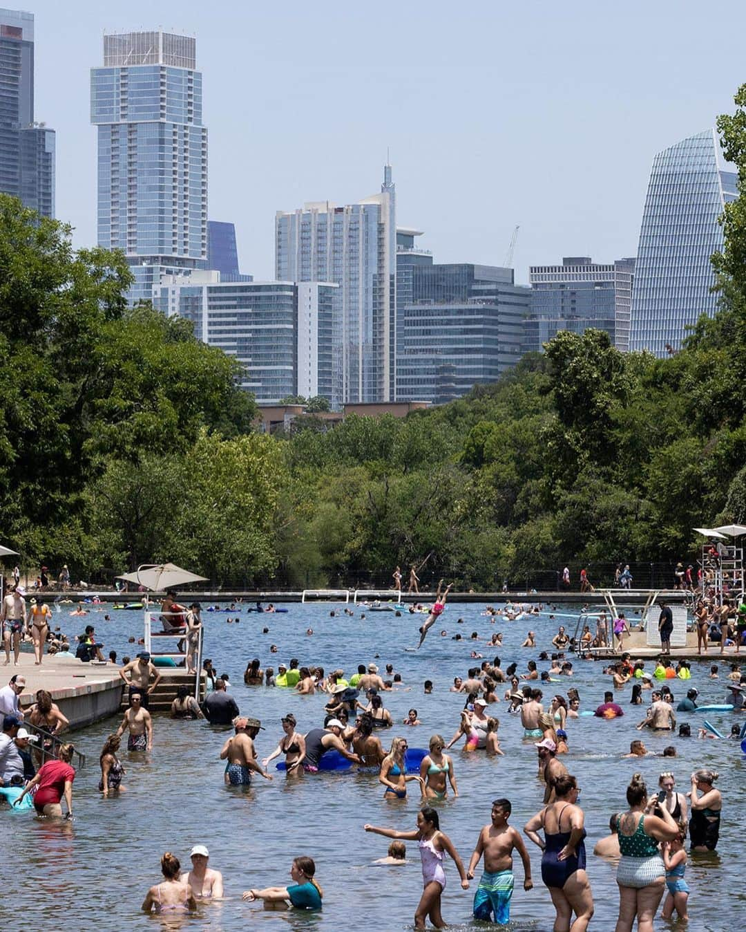 ニューヨーク・タイムズさんのインスタグラム写真 - (ニューヨーク・タイムズInstagram)「Barton Springs Pool, whose cool, natural waters have created summer memories for generations in Austin, Texas, has become an important refuge during the current heat wave.  When Austinites talk about Barton Springs, they do so in almost spiritual terms. “It’s very much a sacred place,” said Kim McKnight, manager of historic preservation and tourism for the city’s Parks and Recreation Department. “I recognize not everybody goes there, but for those who do they can’t imagine life without it.”  A part of the Austin landscape since the early 20th century, the pool is so beloved that residents resorted to near rebellion to save it from developers in the 1990s. Marriages and funerals are regularly held on its grassy banks.  In Austin, where temperatures as high as 107 were forecast to persist through much of the week, the cars kept pulling into the parking lot at the springs, where the water temperature — winter or summer — averages a comfortable 68 to 71 degrees.  Read more about this Austin oasis at the link in our bio. Photos by @ilanapl」7月20日 9時00分 - nytimes