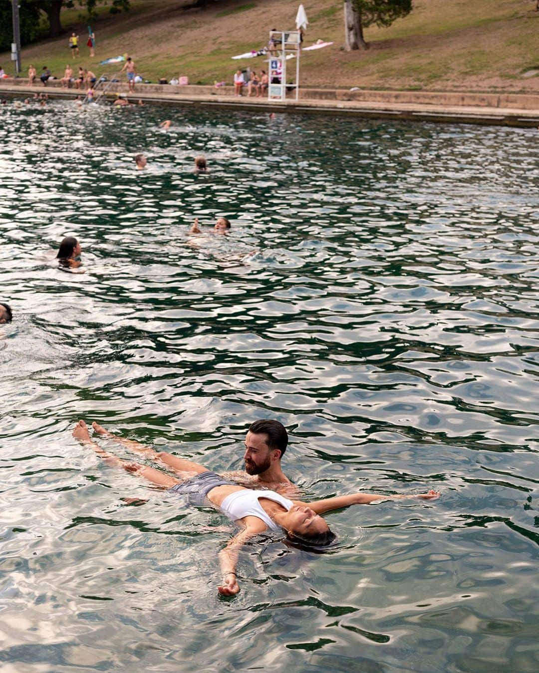 ニューヨーク・タイムズさんのインスタグラム写真 - (ニューヨーク・タイムズInstagram)「Barton Springs Pool, whose cool, natural waters have created summer memories for generations in Austin, Texas, has become an important refuge during the current heat wave.  When Austinites talk about Barton Springs, they do so in almost spiritual terms. “It’s very much a sacred place,” said Kim McKnight, manager of historic preservation and tourism for the city’s Parks and Recreation Department. “I recognize not everybody goes there, but for those who do they can’t imagine life without it.”  A part of the Austin landscape since the early 20th century, the pool is so beloved that residents resorted to near rebellion to save it from developers in the 1990s. Marriages and funerals are regularly held on its grassy banks.  In Austin, where temperatures as high as 107 were forecast to persist through much of the week, the cars kept pulling into the parking lot at the springs, where the water temperature — winter or summer — averages a comfortable 68 to 71 degrees.  Read more about this Austin oasis at the link in our bio. Photos by @ilanapl」7月20日 9時00分 - nytimes