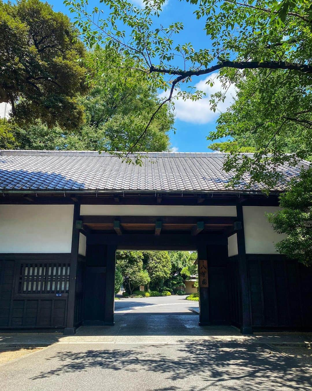 八芳園のインスタグラム：「夏の木漏れ日に包まれる八芳園の「正門」。  威風堂々とした門構えは、「大名門」と「庄屋門」の中間様式で、その格調高い優美な姿が長い歴史の風格を物語ります。  明治年間の造で、当初は草葺でしたが、後に瓦葺となりました。  この正門の向こうに、豊かな自然に恵まれ、四季折々の風情を楽しめる八芳園ならではの景観が広がっています。  🍃✨🍃✨🍃  #八芳園 #結婚式場 #日本庭園 #happoen #初夏を楽しむフォトコンテスト2023  #夏空 #夏 #青空 #今日の空 #日本の四季  #写真好きな人と繋がりたい #東京カメラ部 #その瞬間に物語を #風景写真 #日本家屋 #門 #東京散歩  #japanesegarden #japan_of_insta #japaneseculture #gate #jp_views #special_spot #tokyo #japan_daytime_view #ig_jp #japanoinsta #japantravel #tokyotrip #tokyotokyo」