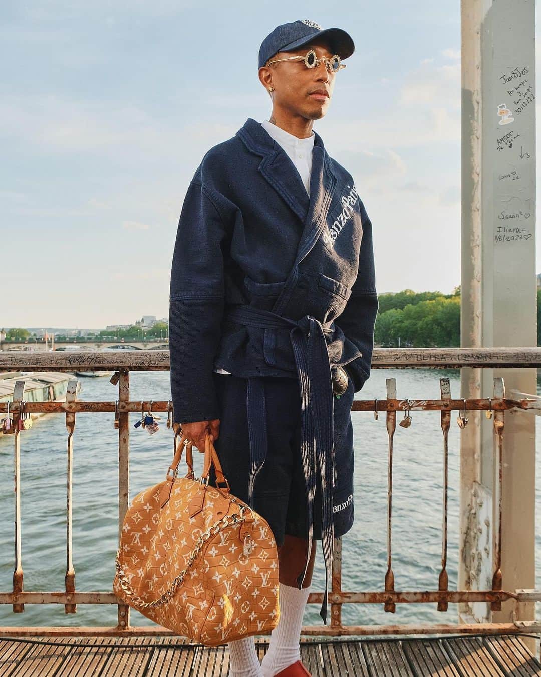 のインスタグラム：「Outside the men’s wear shows in Milan and Paris this month, fashion insiders showed up in inventive looks that included three-piece suits and graphic tees. Pharrell Williams, the new Louis Vuitton men’s creative director, wore a Kenzo jacket-and-shorts set.  The photographer @simbarashecha spent 10 days observing the fashion on the streets of Milan and Paris, where neck scarves were a potent accessory and the few who had traditional neckties wore them atypically, including with collarless shirts.  “It’s not a stretch to say that men’s wear has long been seen by many as simpler and less creative than women’s wear,” he writes. “But as more men have found ways to personalize even the most traditional staples, they have shown that there are far wider possibilities than once thought.”  Others on the street revived a fad popularized in the early 1990s by the hip-hop duo Kriss Kross: wearing blazers and shirts in reverse, so the buttons and lapels were on the back. And there were various graphic tops with popular culture references, including a fisherman’s sweater with an image of Kurt Cobain’s face and a sleeveless tunic featuring the album cover of “Substance” by New Order.  See more style outside from recent fashion weeks at the link in bio. Photos by @simbarashecha」