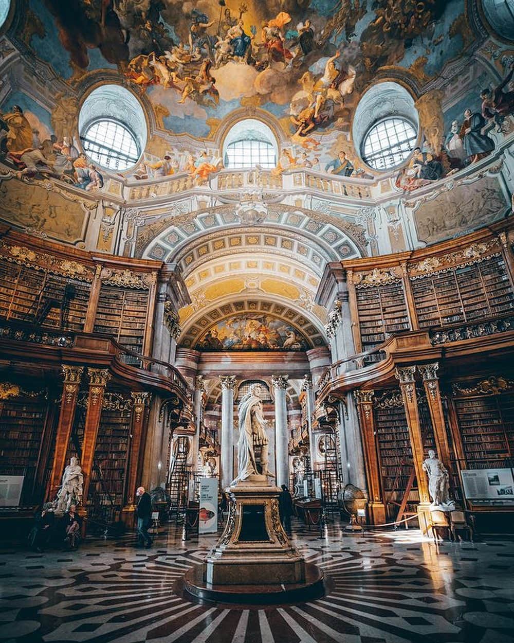 Wien | Viennaのインスタグラム：「You should visit this breathtaking place this weekend! 📚 The Grand Hall of the @nationalbibliothek certainly lives up to its name. At almost 80 meters long and 20 meters in height, it's truly a temple of knowledge. Built in the 18th century as part of the former Court Library, its elaborately decorated dome, numerous frescoes, towering bookshelves with their typical sliding ladders, and gold ornamentation create an opulent setting for the historic treasures it holds. 😍 It houses more than 200,000 volumes dating from 1501 to 1850. 📖 by @bilder_schmiede #ViennaNow  #library #architecture #vienna #vienna_austria #travelgram」