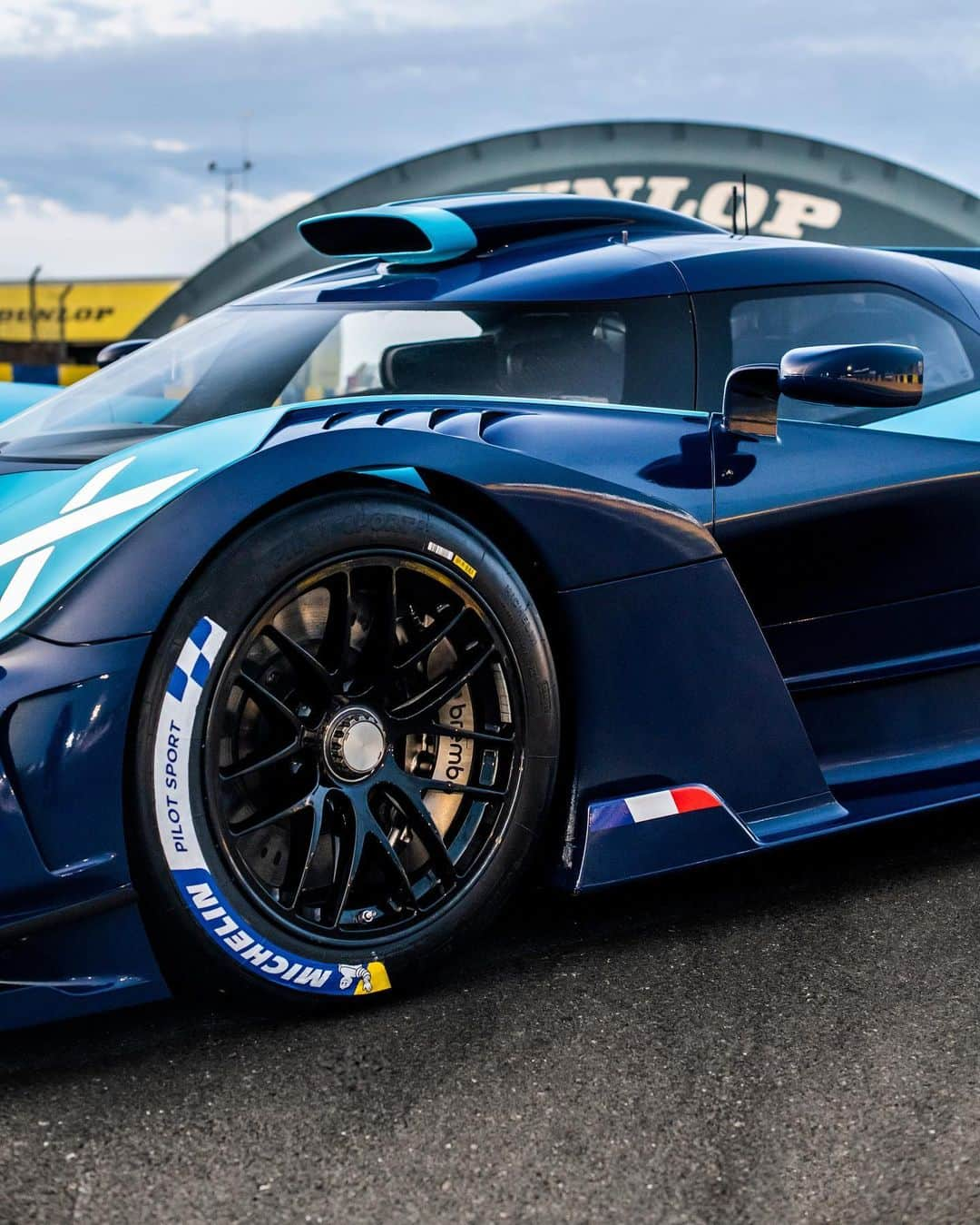 ブガッティのインスタグラム：「The BUGATTI BOLIDE takes to the Circuit de Sarthe to further underscore its advanced aerodynamic capabilities. The results of the ongoing testing program, so far, have been breathtaking. Among the keys to achieving the optimum handling performance is ensuring the correct level of downforce.  The BOLIDE is demonstrating extreme cornering speeds, with up to 2.5 G possible laterally and nearly three tons of downforce generated depending on the speed.  The front diffuser has been developed to improve drivability. The air flowing in is compressed under the front splitter, and then expands under the diffuser, creating suction that pulls the BOLIDE downward.   The BOLIDE’s  rear wing can be adjusted according to each track’s specific characteristics. To set the car up to the exacting needs of the driver, the highly focused aero package can be adjusted to the precise correct balance between downforce and drag.  #BUGATTI #BOLIDE – WLTP: http://bugatti.link/consumption」