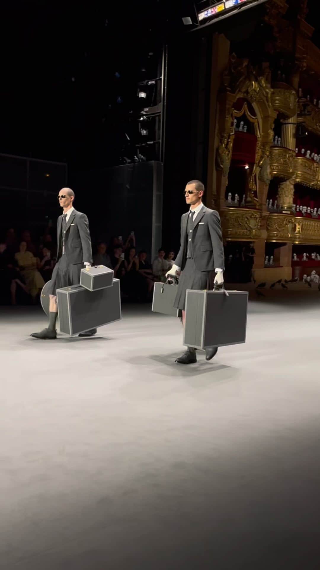 AnOther Magazineのインスタグラム：「At @thombrowne’s inaugural Couture collection presented at Paris’ Palais Garnier – “for one night only” – the American designer presents a twist on classic sportswear through the lens of couture.   Presented to a fake audience of 2,000 onlookers in Thom Browne uniforms and black sunglasses which fill the seats of the opera house, the collection sees solo travellers traversing a station platform. Passengers enter decked in looks of various shades of grey with exaggerated silhouettes. Extravagant tailoring is accented with clusters of beading and sequins, and looks inspired by pigeons tip-toe across the runway. The train finally arrives, but in the form of a sheer white dress that trails ten feet behind.   “Paris is this city that embraces true fashion, true conceptual ideas. It’s really the most important reason I moved,” Browne told AnOther in 2018. “I think fashion is cultural in Paris.”   🎥 by @alexanderfury」