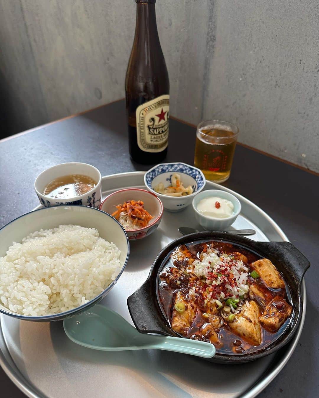 石田一帆のインスタグラム：「. 大好きなランチ☺️🍚  かかんのUberもレトルトもよく食べるけど 2種類の山椒も唐辛子もかけれるしほくほくだし お店で食べるのはやっぱり格別😮‍💨🙏  外だとわんこもOKなのも嬉しい！ ビールが赤星なのも嬉しい！  2.3年前書籍のイベントで出店頂いて 去年 @norm.beer とイベントさせて頂いて ( @newrose_curry さんも🍛♡) 本当ーーに大好きなところ。またすぐ行きたい！ し、イベントまたやりましょう🏊 @shota188   #かかん富ヶ谷#かかん#麻婆豆腐#富ヶ谷ランチ#犬連れ」