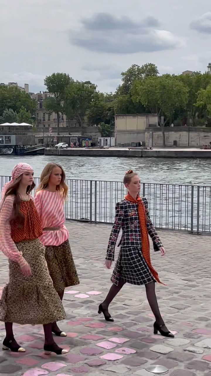 AnOther Magazineのインスタグラム：「Strolling along the Seine with @chanelofficial Autumn/Winter 2023 couture 🇫🇷  Opened by ambassador @carolinedemaigret in a fluid, double breasted black coat, today’s show distils the light, romantic femininity that @virginieviard has established as her signature. Further evolutions of Coco Chanel’s iconic tweed suits come softly feathered, lightweight silks are layered, rippling in the Paris breeze, as models walk the pink cobbled catwalk holding wicker baskets of flowers with dogs in tow.   🎥 by @alexanderfury」
