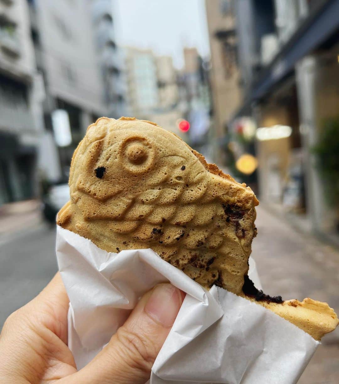 野村真季のインスタグラム：「#たい焼き   麻布十番でのナレーションが定期的に入るようになり、 毎週 商店街を通る度に、食べたいなぁ…と思っていた老舗のたい焼き。 昔はふらっと寄って買えたけど、今や予約が必要になり、近頃はなかなか買うタイミングもなかったのだけど、今日。  小雨がぱらつき始めた夕方、ナレーションから戻る途中、たい焼き屋さんの前に「只今、すぐにお求めになれます」ののぼりが！  買わねば！買わねば！ 勢い込んで一尾ゲット。 焼き立てのたい焼き…一瞬の逡巡はあったけれど、欲に負けて歩きながらパクっ。 薄皮のパリパリ、上品なあんこが隅々までたっぷりと…これこれ、この美味しさですよ。  久しぶりの老舗たい焼きとの邂逅に浮き足立っていたのか、いい年をした大人が歩き食べなんてはしたない、と半分ほど食べて我に返る。←遅い。 リュックに仕舞おうか、このまま食べてしまおうか…。 結果、通りの邪魔にならないビルの端で佇んで食べていると←結局食べる 「あれ、どうしたんですか？」と顔見知りのスタッフに声をかけられた。  まさか彼も私が道端でたい焼きを食べているなんて思わなかったようで、ちょっと驚いた表情を浮かべていたから、すかさず「たい焼き買えたから、つい」と返す。 立ち食いしている理由としてありなのかは分からないけれど、それ以上は突っ込まれなかったのは、彼の優しさなのか戸惑いなのか。  少しの背徳感、溢れる美味しさ、少しの決まり悪さ…一尾を手にした感情のトライアングル。 いい大人なんだけど、いい大人でも、ついね。」