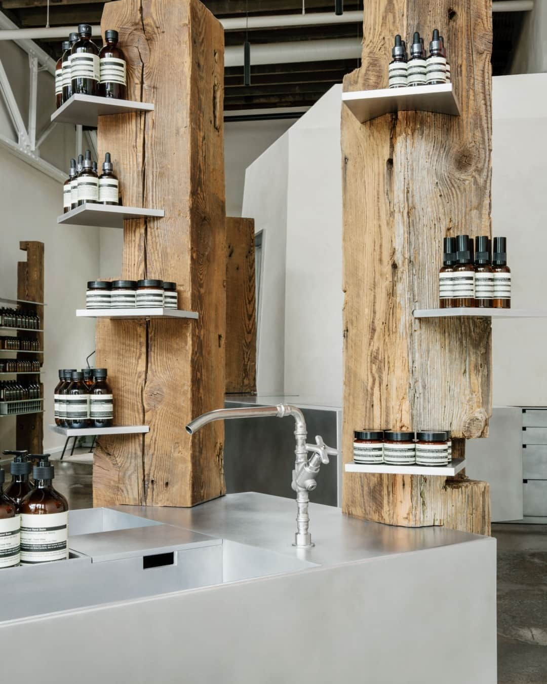 イソップのインスタグラム：「Aesop Edgehill: the marks of time.   The inspiration for this Nashville store, designed in collaboration with Ciguë, grew from the salvaged skeletons of early textile mills and pioneer homes. First-growth Heart Pine logs are arranged vertically, acting both as sculpture and structural support for shelving and storage elements in the light-filled space.   Photography by @cassieflotowarner.」