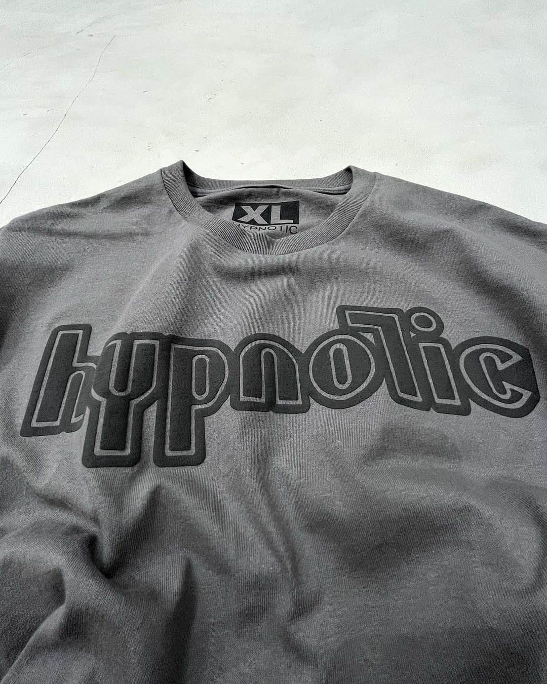 ジャムルのインスタグラム：「@hypnotic_club  Nu-Logo Tee ¥4800 tax in . JAMMRUオリジナルのHYPNOTICから新作の登場です！  判る人には判る！　音ネタ、元ネタ盛り沢山の贅沢デザイン！！  NU-LOGOのデザインはご存知 PRODIGYのロゴ・フォントをイメージ。 そして彼らも在籍したXL recordingsをサンプリングしたサイズ表記に NINE INCH NAILSを意識した黒の発泡プリントというトリプルコンボ！！  シンプルですが、どこかモードでテクノなデザインがお気に入り！　オススメです！！ .  WEB SHOPに入荷しております。 是非ご覧ください。 jammru.com  #お問い合わせはお電話で承ります #jammru#hypnotic_club #osaka  #fashion  #streetstyle  #streetfashion  #vtg  #vintage  #used  #usedclothing  #古着 #古着屋 #ファッション #70s #80s #90s」