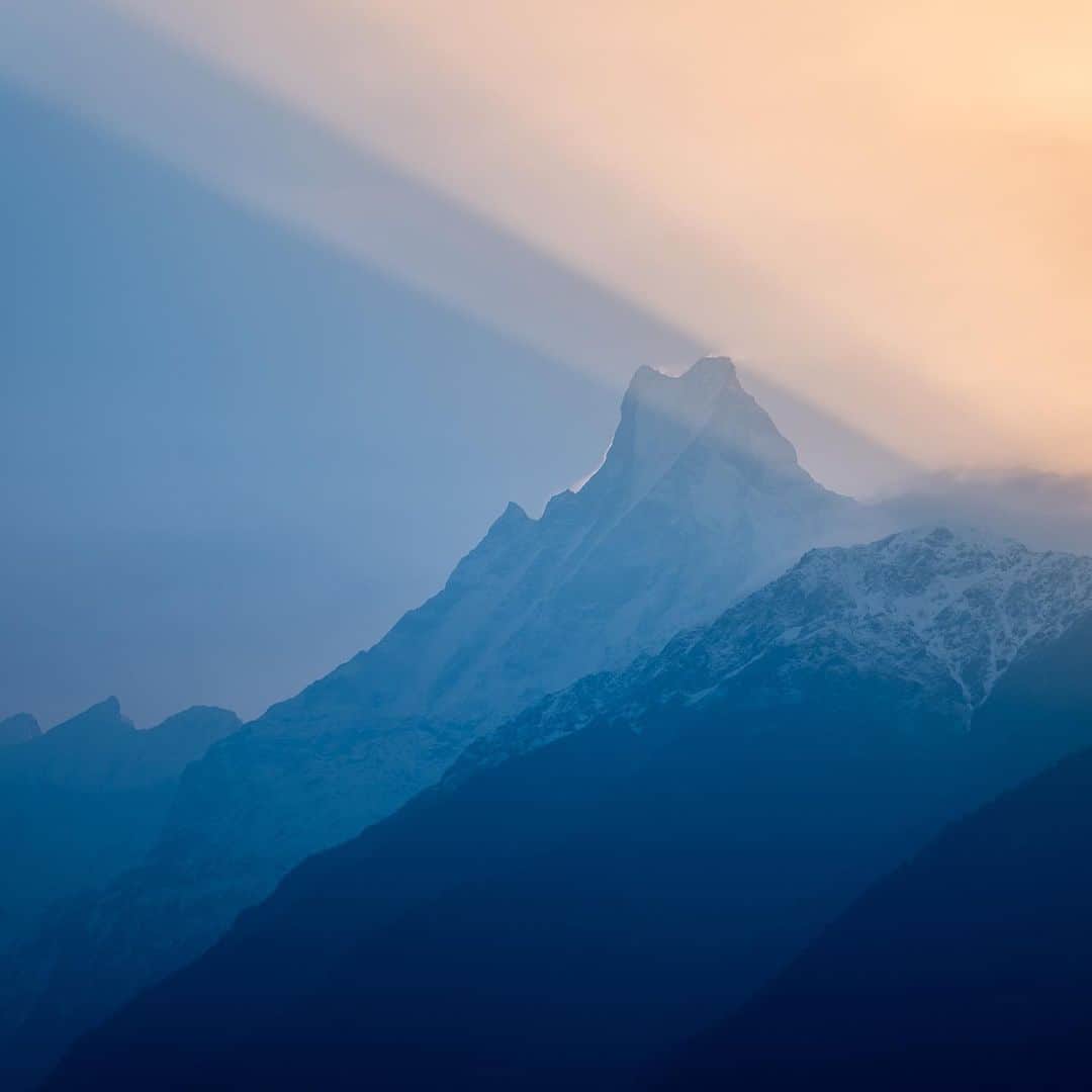 Fujifilm UKのインスタグラム：「Behold the beauty of Machhapuchhare, standing tall at 6,993m! ⛰   @benkapurphotography captured this breathtaking image during sunrise in the charming village of Chomrong during the Annapurna Base Camp trek.  "What is really unique about this image is the light and how fishtail mountain's unique, iconic shape creates streaks of light throughout the sky. It honestly was absolutely incredible to witness."  #FUJIFILMXH2 XF16-55mmF2.8 R LM WR f/8, ISO 125, 1/400 sec.」