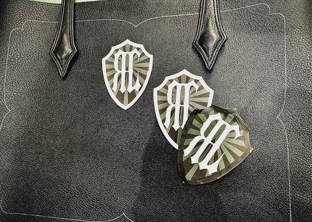 リザード・ヘッドのインスタグラム：「横型トートバッグの制作 ご希望はRHLのシールドタイプをセンターに配置 初めての仕様なのでミリ単位でフィテッング 10パターンから3つに絞って最終調整です。 もちろん紙ではなくレザーのアートワークでビシッと決めます。」