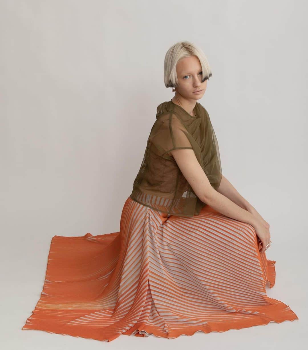 AULA AILAのインスタグラム：「【2023 HIGH SUMMER COLLECTION】  TULLE GATHER TOPS SET COLOR KHAKI×OFF SIZE 0 ¥16,500  ナイロンソフトチュールのトップスと、スリーブレスのカットソーがセットになったアイテム。 チュール部分は、ふんわりと体を包み込むように、アシンメトリーに寄せたギャザーを重ねて、透け感がありながら立体感のある表情に。 単品でワンピースやお手持ちのトップスに重ねて着まわすのもおすすめです。  STRIPE PRINT PLEATS SKIRT COLOR ORANGE×LT.GRAY SIZE 0/1 ¥23,100  細いプリーツとストライププリントの加工を施したオリジナル生地をレイヤードしたスカートです。  内側スカートは左裾にスリットが開いたタイトラインで、表スカートは広げると長方形になるデザイン。 プリーツとストライプの縦柄効果が、造形的でシャープな印象のスカート。  ✔️AULA AILA OFFICIAL WEB STOREにて HIGH SUMMER COLLECTIONアイテム展開中！」