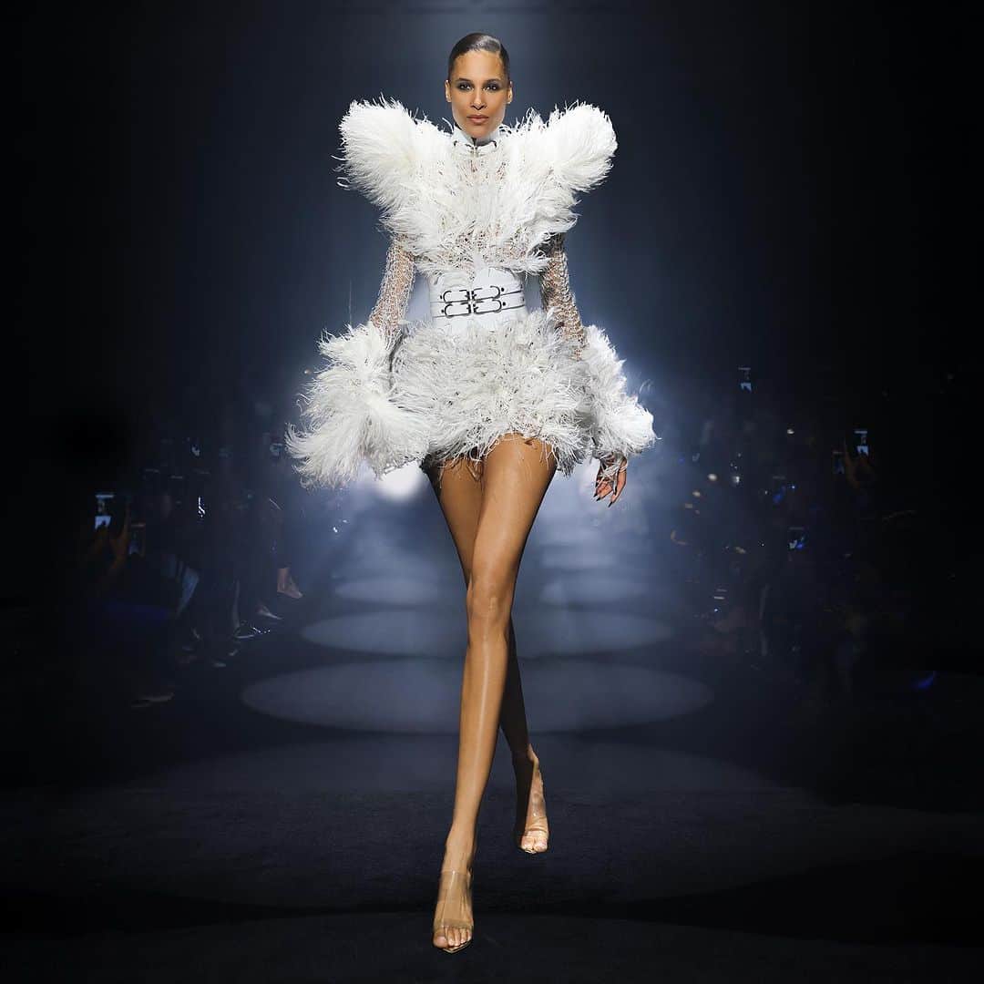 ジュリアンマクドナルドのインスタグラム：「Stepping into a world of enchanting beauty and imaginative grandeur, the extraordinary supermodel @cindybruna navigates the glamorous and utopian JULIEN MACDONALD catwalk in a Couture knit minidress finished with jet-back handmade metallic micro-cut dana and ball-chain beaded fringes, hand-sewn onto and intricate hand-tooled knit-lace and embellished with faceted clear Swarovski crystals.   Finished with hand-sewn stripped coque feathers by the talented @victoriagrant and worn with a couture Super Cinch Waist Belt by none other than @jivomir.domoustchiev  Big thank you to all who contributed to a successful JxG AW24 show  Styling: @karlplewka Makeup: @wendyrowe Hair: @sammcknight1 Nails: @glitterbels Shoes: @charkviani Belts: @jivomir.domoustchiev Tanning: @cocoandeve Production: @mybeautifulcity Movement Direction: @officialroyston Music: @djsmokinjo Casting: @angusctmunro PR: @purplepr Official Sponsor: @weshopsocial」