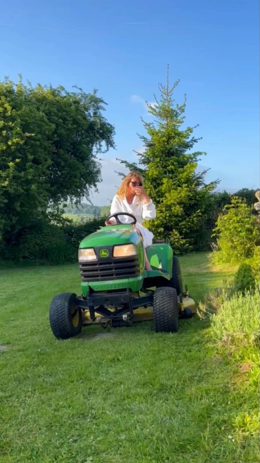 キャット・ディーリーのインスタグラム：「Apparently it’s #NationalRelaxationDay today… and I mean what’s more relaxing than driving a tractor through the English countryside in your best bathrobe, with a martini that’s really just water & some olives (seriously) by your side?! 🍸🚜😎🌳💅🏻」