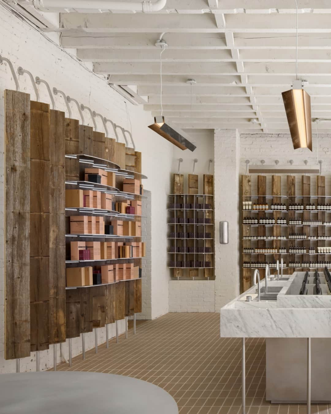 イソップさんのインスタグラム写真 - (イソップInstagram)「Aesop Nolita—familiar yet transfigured.   After almost two years of operating in a temporary design, Aesop Nolita is now open in its permanent guise. Inside, cylindrical counters reference the water towers which have been perching atop the borough’s roofs for over 100 years. Cedar planks bearing the patina of decades of water storage were reclaimed from them to become uprights for shelves—they sit in dialogue with the exposed joists of the ceiling, exchanging stories of Nolita’s past.    Photography by @rafaelgamo」8月12日 18時00分 - aesopskincare