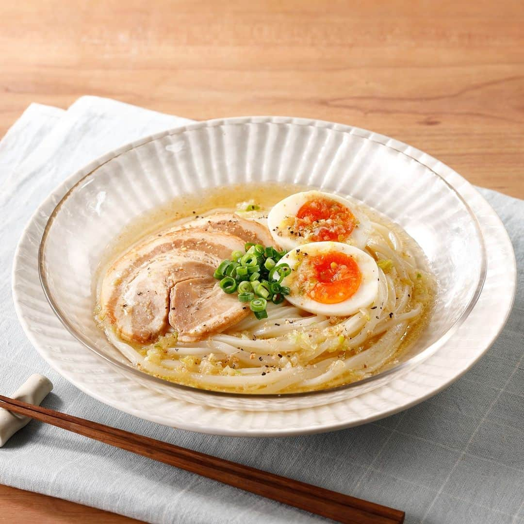 テーブルマークのインスタグラム：「. レンジで簡単！夏うどん⛱️ 【冷やしねぎ塩ラーメン風うどん】 . 山本ゆりさん考案！ 冷たいさっぱりねぎ塩だれのうどんは暑い日にぴったり🍜🧊 . ▼材料（１人分） ❁冷凍「稲庭風うどん」：１玉 ❁長ねぎ（みじん切り）：1/4本 ❁氷：約80ｇ（一般的な製氷機の氷を約10個） ❁青ねぎ（小口切り）、チャーシュー（市販）、 　半熟卵、白すりごま、粗びき黒こしょう：お好みで ［Ａ］ ❁鶏がらスープの素（顆粒）：小さじ２ ❁にんにく（すりおろし）：小さじ1/2 ❁しょうが（すりおろし）：小さじ1/2 ❁ごま油：大さじ１ ❁水：大さじ１ . ▼下準備 ・冷凍「稲庭風うどん」はレンジで加熱し、 　冷水でしめて水気を切っておく。 . ▼作り方 ①長ねぎを耐熱容器に入れ、 　［Ａ］を加えてふんわりとラップをかけて、 　レンジ（600W）で1分30秒加熱する。 　よく混ぜて氷を入れて冷やす。 . ②うどんを器に盛り、 　お好みで青ねぎ、チャーシュー、 　半熟卵をのせ、①をかける。 . ③白すりごま、粗びき黒こしょうを 　お好みでかけて召しあがれ。 . #うどん #udon #冷凍うどん #稲庭風うどん #うどん部 #うどん好き #レシピ #おうちごはん #簡単レシピ #うどんレシピ #アレンジレシピ #今日のごはん #ランチ #ランチメニュー #夕食 #晩御飯 #晩ご飯 #晩ごはん #TableMark #テーブルマーク #冷やしうどん #レンチンレシピ #レンジ調理 #夏うどん #夏 #夏レシピ #夏メニュー」