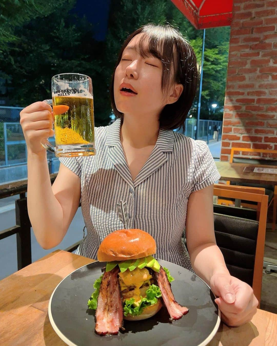 蒼井まやのインスタグラム：「. 今日はどこへ行こうか 今日はどこで飲もうか  ハピネスを求めて到着したのは…そう！池袋！  さぁ今日はがっつり食べるぞ～！ 駅からトコトコ歩いて5分くらい〜  「BROOKLYN MILLS」  本場ニューヨークをイメージした内装🇺🇸 ハンバーガーが美味しそうで🍔✨ ちょっといいハンバーガーってたまに食べたくなるよね？  🍔アボカドベーコンチェダーチーズバーガー 🍺生ビール  今日はこのセットでハピネスチャージ👼🩵 テラス席が良い風吹いて気持ちよくて 生ビール飲みながらハンバーガーの到着を待ちます🍻  そしてやってきたハンバーガー。  アボカドどかーん！！！ チーズとソースがたっぷり溢れ出てて！！！ ベーコンはみ出しすぎィ！！！！  ああもう絶景…  アボカド入りのハンバーガーなんてさ。 もう好きに決まってんじゃん。 はい勝ち確です。  パティは国産牛100%🐃 溢れ出る肉汁にニヤニヤが止まらない。 チーズとの相性はもう言わずもがな。 玉ねぎも甘くて最高に美味しい。 ベーコンはスモーキーで食べ応え抜群。 このベーコンだけでビール3杯はいけるね。  などと考える暇もないくらい美味しくて 食べてる時はめちゃくちゃ夢中になって食べてしまった。 あっというまに完食です。ご馳走様でした。  かなりボリューミーだけど全体のバランスがすごくいいので 飽きずに最後まで美味しく食べられました🫶✨  BBQコースもあるみたいで 次はそちらで女子会などしたいと思ったの巻◎  🎪 BROOKLYN MILLS 📍 東京都豊島区南池袋2-22-1 第3高村ビル 1F 🚃池袋駅 徒歩5分  PR @brooklynmills_ikebukuro #brooklynmills #グルメバーガー #池袋ハンバーガー #池袋カフェ #池袋グルメ #ハンバーガー女子 #ハンバーガー食べたい #ハンバーガー愛好家 #ハンバーガー好き #ハンバーガー🍔」