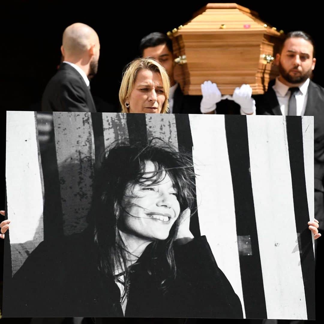 WWDジャパンさんのインスタグラム写真 - (WWDジャパンInstagram)「ニュース：故ジェーン・バーキンの葬儀、娘のシャルロット・ゲンズブールやルー・ドワイヨンらが参列  7月16日に76歳で死去したイギリスの俳優でシンガーのジェーン・バーキン（Jane Birkin）の葬儀が24日、パリのサン・ロック教会で行われた。バーキンの次女シャルロット・ゲンズブール（Charlotte Gainsbourg）と三女ルー・ドワイヨン（Lou Doillon）をはじめとする親族のほか、ブリジット・マクロン（Brigitte Macron）仏大統領夫人、リマ・アブドゥル・マラク（Rima Abdul Malak）仏文化大臣、カトリーヌ・ドヌーヴ（Catherine Deneuve）とその娘であるキアラ・マストロヤンニ（Chiara Mastroianni）、ヴァネッサ・パラディ（Vanessa Paradis）、キャロル・ブーケ（Carole Bouquet）、シャーロット・ランプリング（Charlotte Rampling）、アンソニー・ヴァカレロ（Anthony Vaccarello）「サンローラン（SAINT LAURENT）」クリエイティブ・ディレクターらが参列し、故人を偲んだ。  教会に棺を運び込む際には、男性たちと共にシャルロットとルーも棺を担いだ。葬儀で、シャルロットは「（ジェーンが）いなくなったことで、皆さんの魂が苦しんでいることが伝わってきます。私たちの中には、彼女が残していった空洞があります。彼女は私の母であり、私たちの母でした」と語った。ルーは母との思い出を話した後、「あなたがくれた全ての冒険に、そしてあなたが平凡で、中庸で、従順な人ではなかったことに感謝します。（あなたのいない）明日からのこの世界は、とても平穏で整然としているだろうことを思い、すでに動揺しています」と述べた。  葬儀は家族と関係者のみで執り行われたが、その様子は教会の外に設置されたスクリーンに映し出されており、周辺に集まった多くのファンも故人を悼んだ。葬儀が終わり、教会から棺を運び出す場面では、1991年に亡くなったパートナーのセルジュ・ゲンズブール（Serge Gainsbourg）が作詞・作曲し、バーキンが歌う「ラ・ジャヴァネーズ（La Javanaise）」が流されたという。バーキンの棺はパリのモンパルナス墓地に移され、ゲンズブールと2013年に亡くなった長女のケイト・バリー（Kate Barry）の隣に埋葬される。  詳細は @wwd_jp プロフィールのリンクから  JULIEN DE ROSA/AFP GETTY IMAGES ©︎FAIRCHILD PUBLISHING, LLC  #janebirkin#birkin#ジェーンバーキン#バーキン#葬儀#charlottegainsbourg#loudoillon#vanessaparadis#catherinedeneuve」7月25日 16時06分 - wwd_jp