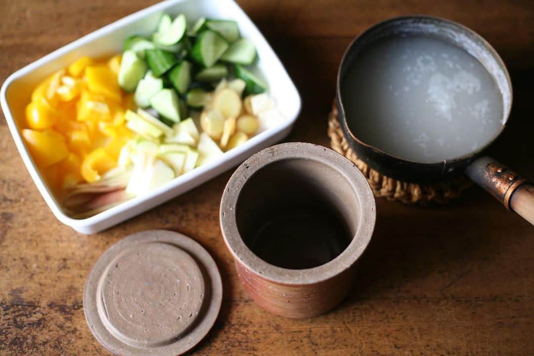職人.comさんのインスタグラム写真 - (職人.comInstagram)「【フードコンテナで作る水キムチ】  仕込み時間も短く、少ない野菜でも簡単に漬けることができる韓国の「水キムチ」。日本の浅漬けのような感覚で、シャキシャキとさっぱりした食感は、夏の暑い時期の元気を回復するのに一役買ってくれます。もちろん夏だけではなく一年を通して作って食べることができ、冷え込みの厳しい朝鮮半島では、冬に不足するビタミンや乳酸菌を補うため、白菜や大根で水キムチを作り置きしていたそうです。  水キムチは、野菜に自然に付着している乳酸菌が米のとぎ汁やりんごの糖分を素にして発酵する仕組みで、ドイツのザワークラウトと同じ乳酸発酵を利用しています。植物性の乳酸菌は、私たちの腸に存在している腸内細菌の餌となり、腸内環境を整え活性化してくれる働きがあるため、免疫力アップや生活習慣病の予防、ストレスへの耐性、美肌効果などが期待されています。  そんな水キムチを、一陽窯のフードコンテナを使って作ってみました。夏という季節も手伝って、丸一日たたないうちにしっかりと発酵し、爽やかな酸味とシャキッとした野菜の歯ごたえが嬉しくなる出来栄えです。色鮮やかなパプリカは、漬物として食べるとピクルスのような感覚で、定番のきゅうりは安定のおいしさ、りんごの甘みが全体の酸味をバランスよく調和させてくれ、味見のつもりがついつい一つ二つと食べ進めてしまいました。柔らかな銀色に輝く大寺幸八郎商店のかなまり小に盛り付ければ、暑い夏のテーブルにも涼しさを届けることができるでしょう。  備前焼のフードコンテナは「多孔質」が特徴であり、その表面には無数の小さな穴が空いているため、通気性に優れています。また、この素材は乳酸菌や酵母の生息地になりやすく、発酵や熟成を進めるのに理想的な環境を作り出してくれます。大きいサイズのフードコンテナは、水キムチのほかにも塩麹やひしおの仕込みに、小さいサイズは塩やマスタードの調味料入れなどにご利用いただけます。  最後に「水キムチはスープを味わう」といわれるくらい漬け汁にはうまみが含まれ、キムチと一緒に味わっても、冷麺のスープベースや、一風変わった素麺のたれとしても活用することもできます。おすすめは、残った漬け汁に千切りにしたきゅうりとみょうがを入れ、塩と黒胡椒で味を調え、お好みで氷を浮かべて作る冷たいスープ。たっぷり含まれている乳酸菌をおいしく楽しく摂りながら、この先の長い夏を乗り切っていきましょう。  [材料] きゅうり　1本 パプリカ　1個 りんご　1/4個 みょうが　2本 にんにく　大1かけ 生姜　1かけ  塩　小さじ2 砂糖　小さじ1 赤唐辛子　2本（辛さはお好みで調整してください） 米のとぎ汁　500ml  [作り方] 1. 米のとぎ汁（最初の方の濃い目のもの）、塩、砂糖を火にかけて沸騰させる。煮立ったら火を消し、粗熱を取る。 2. きゅうりとパプリカは乱切りにする。りんごは皮付きのまま1/4にカットし、薄切りにする。 3. にんにくは半分に、みょうがは縦半分に切ってから更に半分に切る。生姜は薄くスライスする。 4. 野菜と赤唐辛子を清潔な容器に入れ、野菜の全量がかぶるくらいまで1の漬け汁を注ぐ。 5. 常温で夏場は1日程度、冬場は2～3日置き、発酵したら冷蔵庫で保存する。一週間をめどに食べきる。  一陽窯　フードコンテナ https://www.shokunin.com/jp/ichiyou/container.html 中村銅器製作所　行平鍋 小 https://www.shokunin.com/jp/nakamuradouki/yukihira.html 野田琺瑯　レクタングル浅型M シール蓋付 https://www.shokunin.com/jp/noda/ 大寺幸八郎商店　かなまり 小 https://www.shokunin.com/jp/otera/kanamari.html 青龍窯　小鉢 https://www.shokunin.com/jp/seiryu/kobachi.html  参考資料 https://hanako.tokyo/learn/144401/ https://www.villalodola.jp/magazine/column-285/ https://haccomachi.jp/recipe/7597/  @shokunincom  #職人ドットコム #一陽窯 #フードコンテナ #備前焼 #備前焼き #備前焼のある暮らし #備前焼作家 #備前焼を使う #備前焼のある食卓 #水キムチ #野田琺瑯 #大寺幸八郎商店 #かなまり ##青龍窯 #平清水焼 #平清水焼き #平清水焼のある暮らし #平清水焼青龍窯 #平清水焼の器 #中村銅器 #中村銅器製作所 #銅製行平鍋 #自家製キムチ #自家製水キムチ #一陽窯のフードコンテナ #フードコンテナー #備前焼の保存容器 #備前焼の器 #行平鍋」7月26日 21時41分 - shokunincom