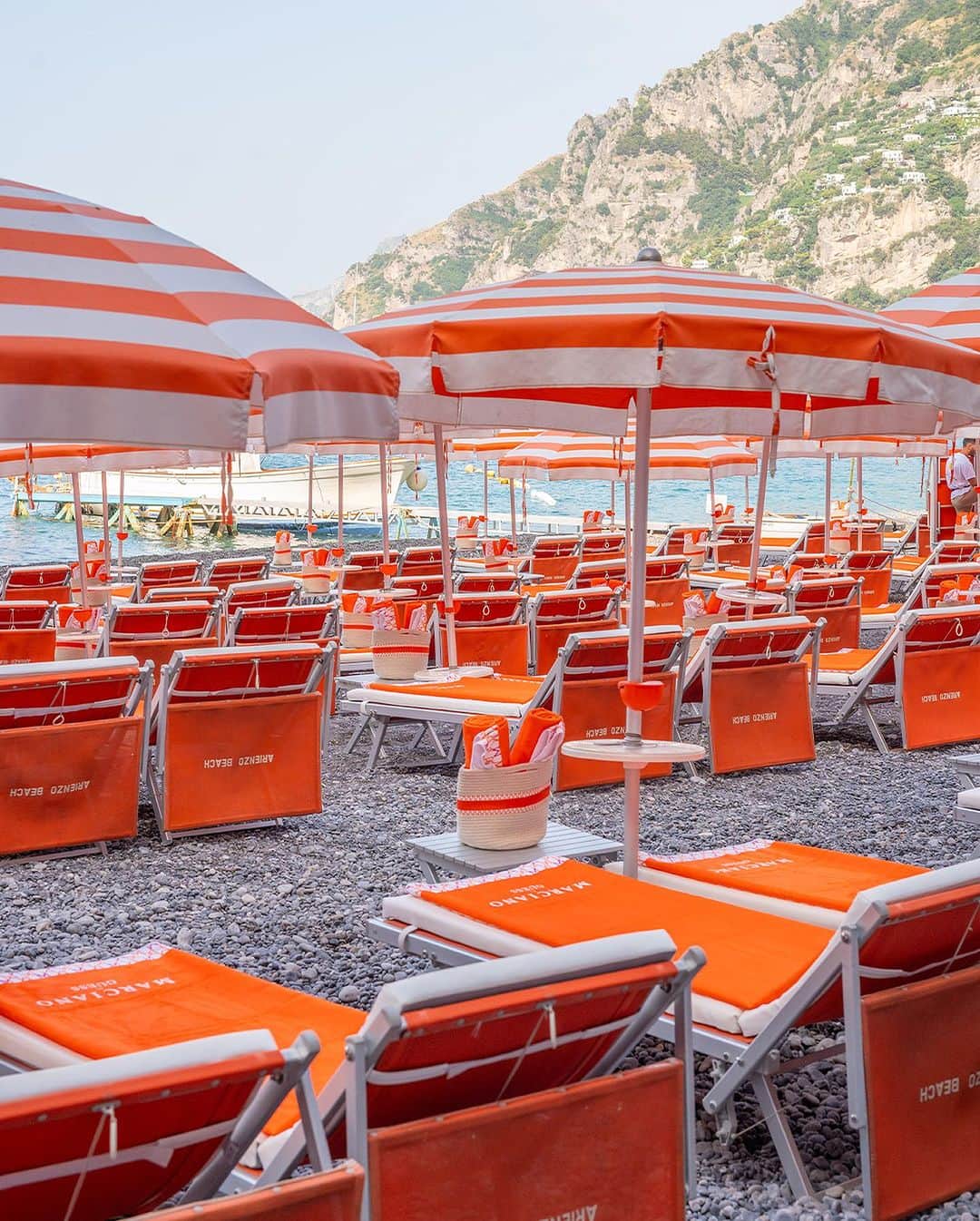 ゲスのインスタグラム：「Ciao, Positano. The Marciano Beach Club at @arienzobeachclubpositano looks out over the mesmerizing blue of the Tyrrhenian Sea, in a luxe, laid-back atmosphere, where guests can relax in an oasis of peace and tranquility. Our signature logo accent from the #Marciano collection covers the loungers, towels, cushions, and accessories, for a summery, sophisticated finish. #MarcianoPositano #GUESSBeachClub」