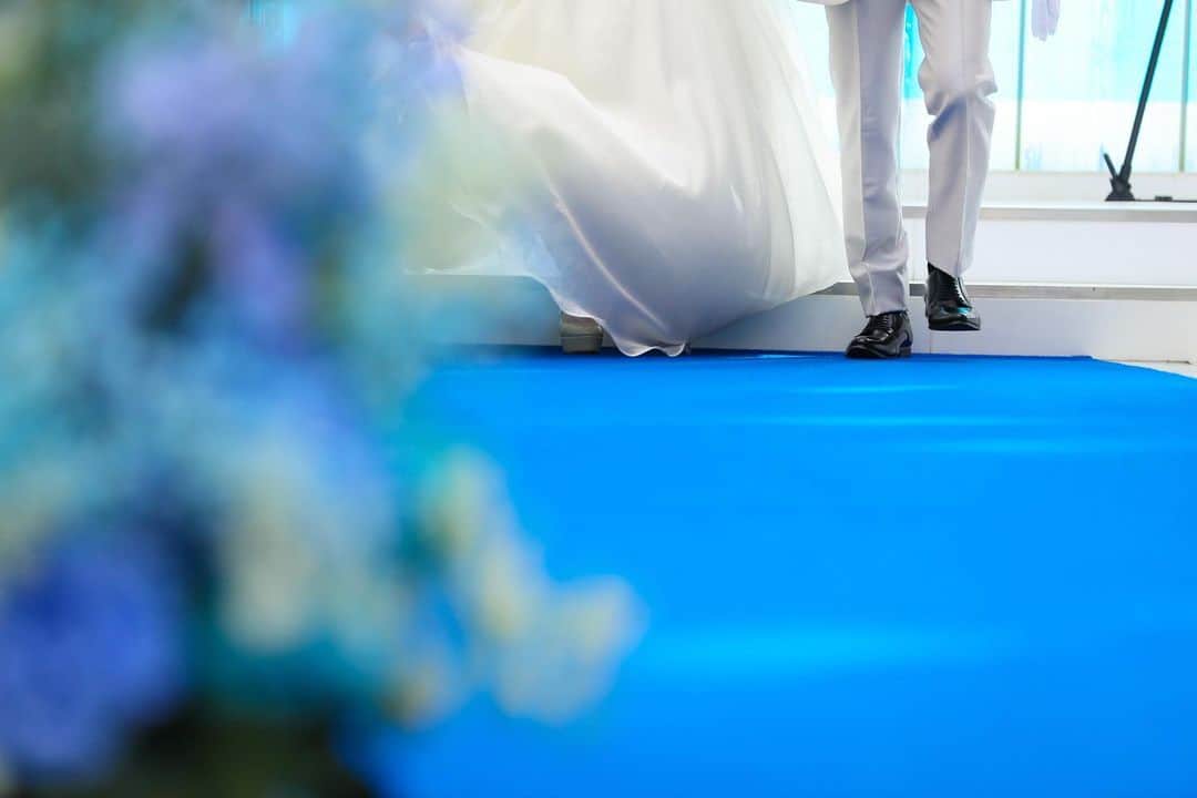 ルミアモーレのインスタグラム：「. ルミアモーレの 青いバージンロード🕊  「果てしなく続く青い空や海のように永遠に続く愛」という 意味が込められています…！  白いウェディングドレスは青い バージンロードにとっても映えます！ ぜひご見学にお越しください✨   #結婚式場 #結婚式場探し   #結婚式場見学   #ウェディングフォト    #青いバージンロード   #東京結婚式場    #プレ花嫁さんと繋がりたい」