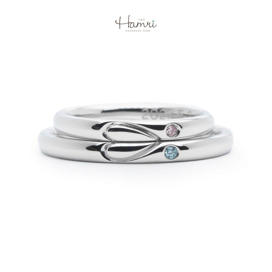 結婚指輪・婚約指輪『Hamri(ハムリ)』のインスタグラム：「【手作り結婚指輪】  シンプルなストレート、 甲丸の指輪にお二人の指輪を重ねてできる、 ハートの彫りをお入しれたデザインです♡  線彫りの丸みのあるハートが可愛らしい印象ですが、 それぞれ身につけていただく際にはシンプルなラインが入った、 普段使いもしやすいデザインになります。  また、お二人それぞれのお好きなカラーダイヤモンドをお留めして 内側にはお二人の記念日とお名前が刻印されています。  ペア感のあるお二人ならではの指輪が完成いたしました！  ご結婚おめでとうございます！   ==========================  ♦︎♢指輪制作の写真や動画を無料撮影、全データプレゼント♢♦︎  DMやLINEでのご相談お待ちしております♥ ⇒@hamri_omotesando  ❁・❁・❁・❁・❁・❁・❁・❁・❁・❁・❁  ＊結婚指輪・婚約指輪セットリング5%OFF＊  @hamri_omotesando  Hamri「ハムリ」  〒150-0001 東京都渋谷区神宮前5-11-11 2F  tel 0120-121-175 hp https://hamri.jp/  open 11:00〜19:00 close 火/水　祝日営業  ❁・❁・❁・❁・❁・❁・❁・❁・❁・❁・❁  #手作り結婚指輪  #結婚指輪 #マリッジリング  #プレ花嫁 #Hamri #Hamri表参道 #オーダーメイドリング #鋳造 #ブライダルリング #ペアリング #ピンクダイヤモンド #プラチナリング #アイスブルーダイヤモンド #シャンパンゴールド #ゴールドリング #コンビネーションリング #2023wedding #2023春婚 #2023夏婚 #プレ花嫁準備 #プレ花嫁と繋がりたい #結婚指輪探し #結婚指輪選び #結婚準備  《Hamri検索タグ》  #Hamriデザイン #Hamri指輪作り #Hamri花嫁」