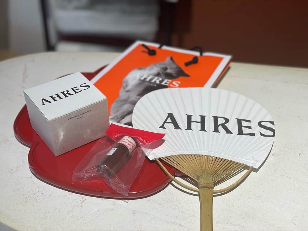小橋めぐみのインスタグラム：「クレンジングタイムが癒しタイムに💛  @ahres_official の、真っ黒なクレンジングバーム。この黒さは紀州産の梅炭。毛穴の奥の汚れまできっちり吸着してくれる。 肌にのせると、とろけるように伸びてメイクに馴染んでいく感じが、とても気持ちいい。 香りは、シトラスウッディの精油ブレンド、ジンジャー、レモングラス、ヒノキetc 爽やかで、気持ちもリフレッシュできて、ダブル洗顔不要。ぬめり感なし。でも突っ張らない。価格もお手頃。 いいことだらけ。  路面店で購入したのですが、うちわに香水を振りかけてプレゼントしてくれました。 ショップバッグも可愛い❤️  #アーレス #ahres #お気に入りコスメ」