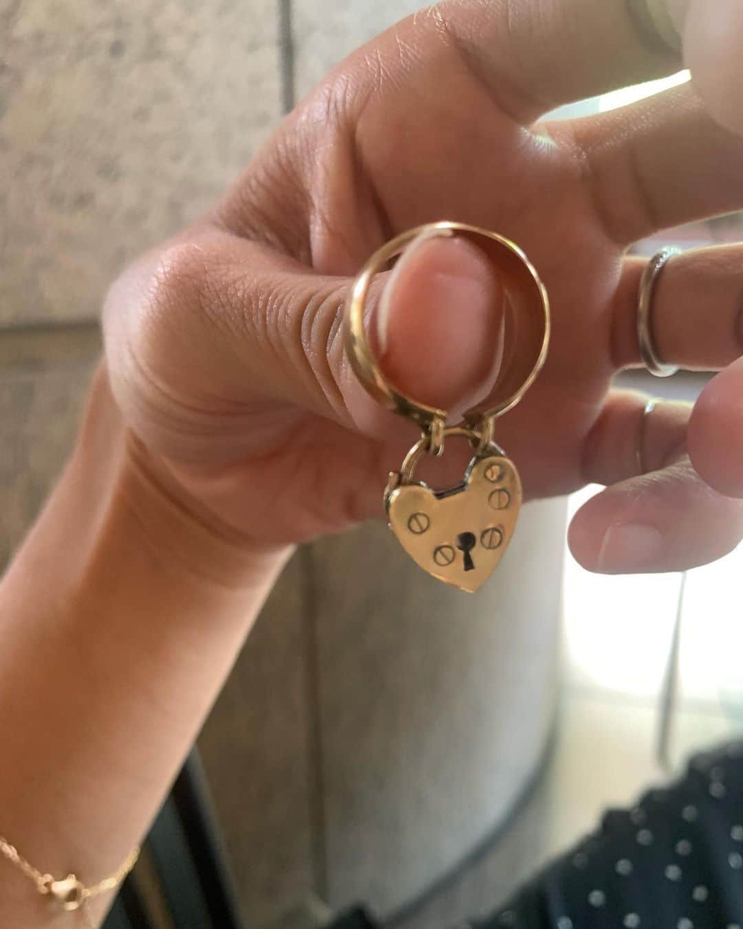 馬渕真由子のインスタグラム：「lock my heart ring🔐  vintageデザインでモチーフとして見かけるハートのパドロックは変わることのない愛を意味しますが、PARCAのこのリングに込めた思いはアイテムの名前の通り 「心に鍵をかけて」。  "大切な記憶や思い出、自分だけの秘密をそっと心に忍ばせて鍵をかける。"  ハートのパドロック部の中身は空洞になっているので付けていて重さが気になることは(個人的な感想で言えば)ありません。  リングのアーム部分にしっかり幅をもたせたことで、可愛くなりすぎないように。Vintageの風合いを出すためにK18GPT以外は全ていぶし加工を行っています。  パドロック部のマイナスドライバーで閉められているデザイン部分、これはオリジナルのタガメを制作してもらい一つ一つ打ち込んでもらっています。 そしてこのパドロック、なんとちゃんと開閉します。このギミックに私はときめきを感じることを禁じ得ません。🗝️」