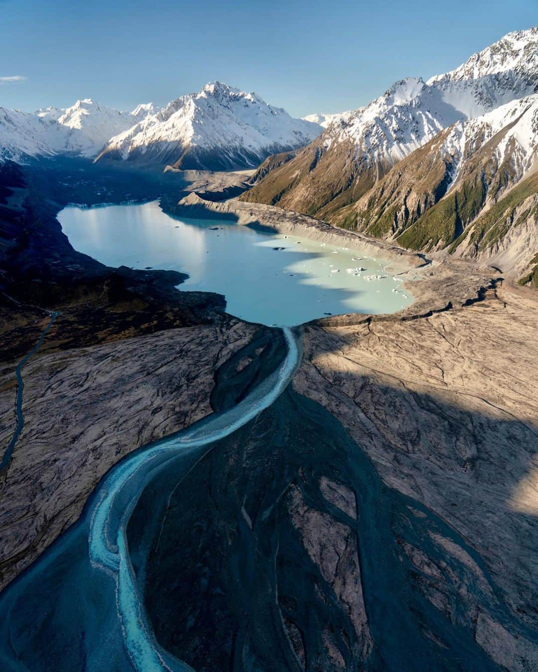 クリス・バーカードのインスタグラム：「It’s a funny tension… we build roads & structures to keep us protected from the often inhospitable elements but find ourselves continually coming back to these natural places to feel most alive.  In 2018, Icebreaker reached out to me about an assignment to document the Tasman Glacier located in Mount Cook National Park… to create a photo meant to represent our relationship with nature and in this case, the glacier. I felt like showing the expanse of the ice, it’s context to the mountain range, and the eventual flow into a body of water would be most impactful through a wide lense from the window of a Cessna high above. Even with the rattling of the aluminum and hum of the small engine and personal feelings of fragility, the peace & majesty of the landscape couldn’t help but leave an impression on me.   Shot on @sonyalpha A7RIII // 24-105mm f/4   Shutter: 1/320  ISO: 100  Aperture: f/4」
