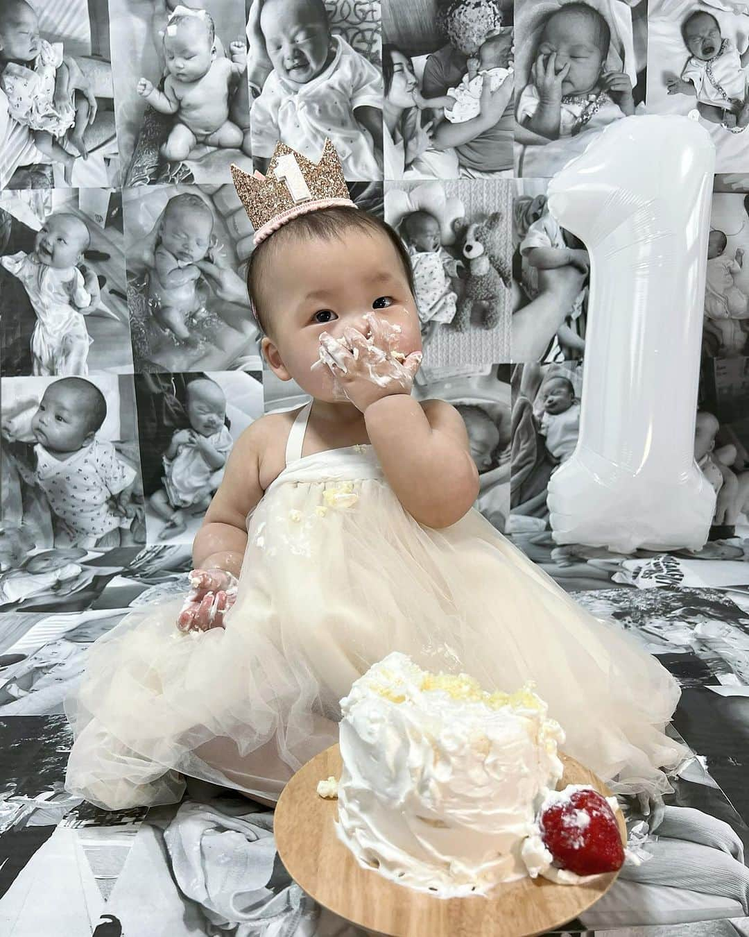 春咲ひなたのインスタグラム：「👼🏻🎂  あっという間に1歳になっちゃった🥹 人生初のケーキも爆食で パパと一緒に作った甲斐がありました🫶🏻  この背景、家でスキマ時間に作ってて 用紙がA4しか無かったから死ぬほど大変だったの。 (まじ頑張ったまじ愛) 今からやるよってママは絶対にコンビニでやった方がいいよ。 絶対。w  帽子拒否始まったから諦めてたのに 空気読んでクラウンちゃんと着けてくれて ママはゔれじぃありがどゔ👑🩷  #1歳誕生日#スマッシュケーキ#おうちスタジオ」