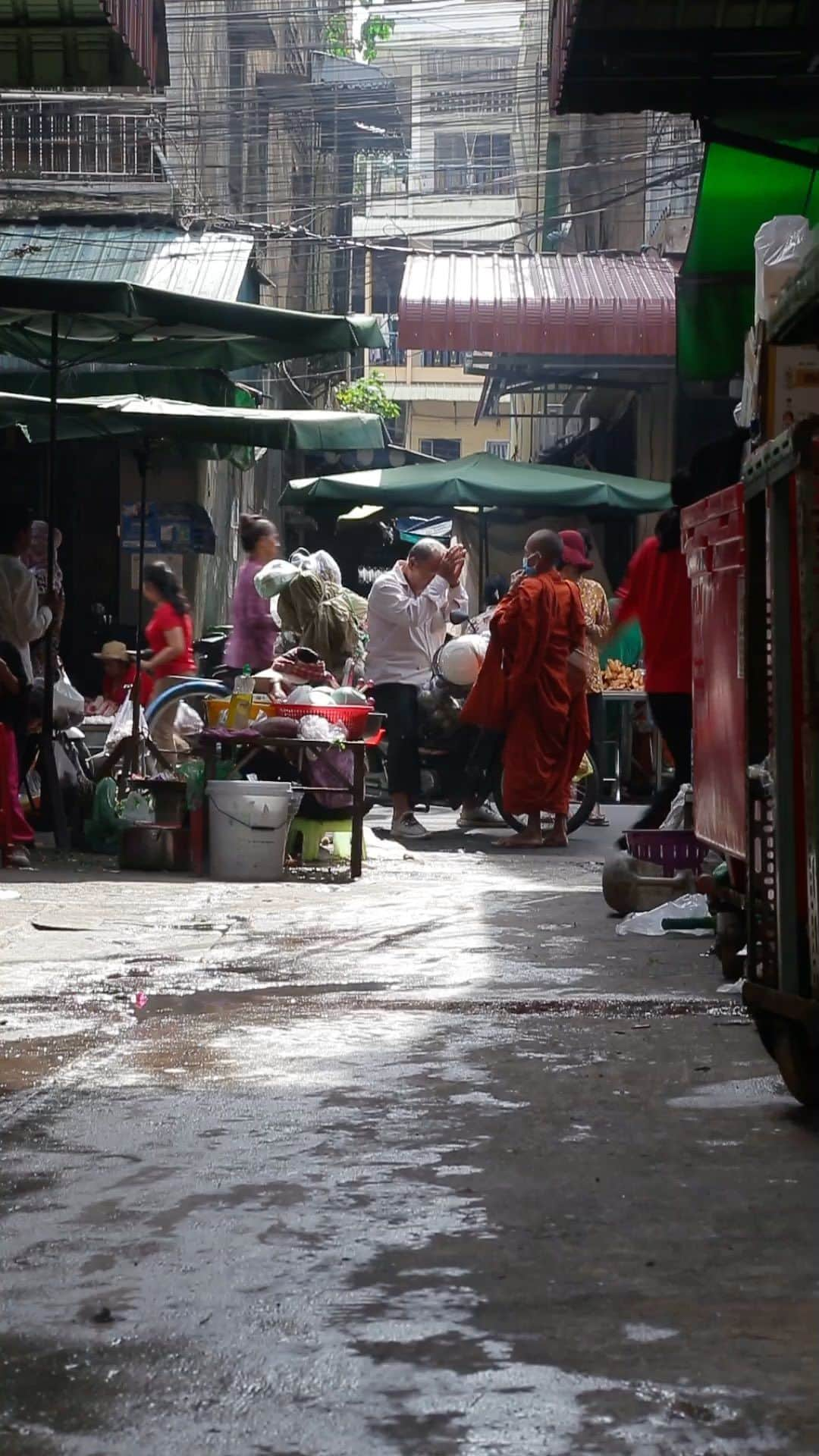 Shunsuke Miyatakeのインスタグラム：「Blessing in the morning / Phnom Penh, Cambodia   There are tons of small alleys around Orussey Market. Smoke from the street vendors, TukTuks and Cyclos driving around, kids running around, granny going for shopping, young man going to work, and young monk blessing the grandpa.  Between the alleys, we can see the raw and real life with great lights in the morning.」