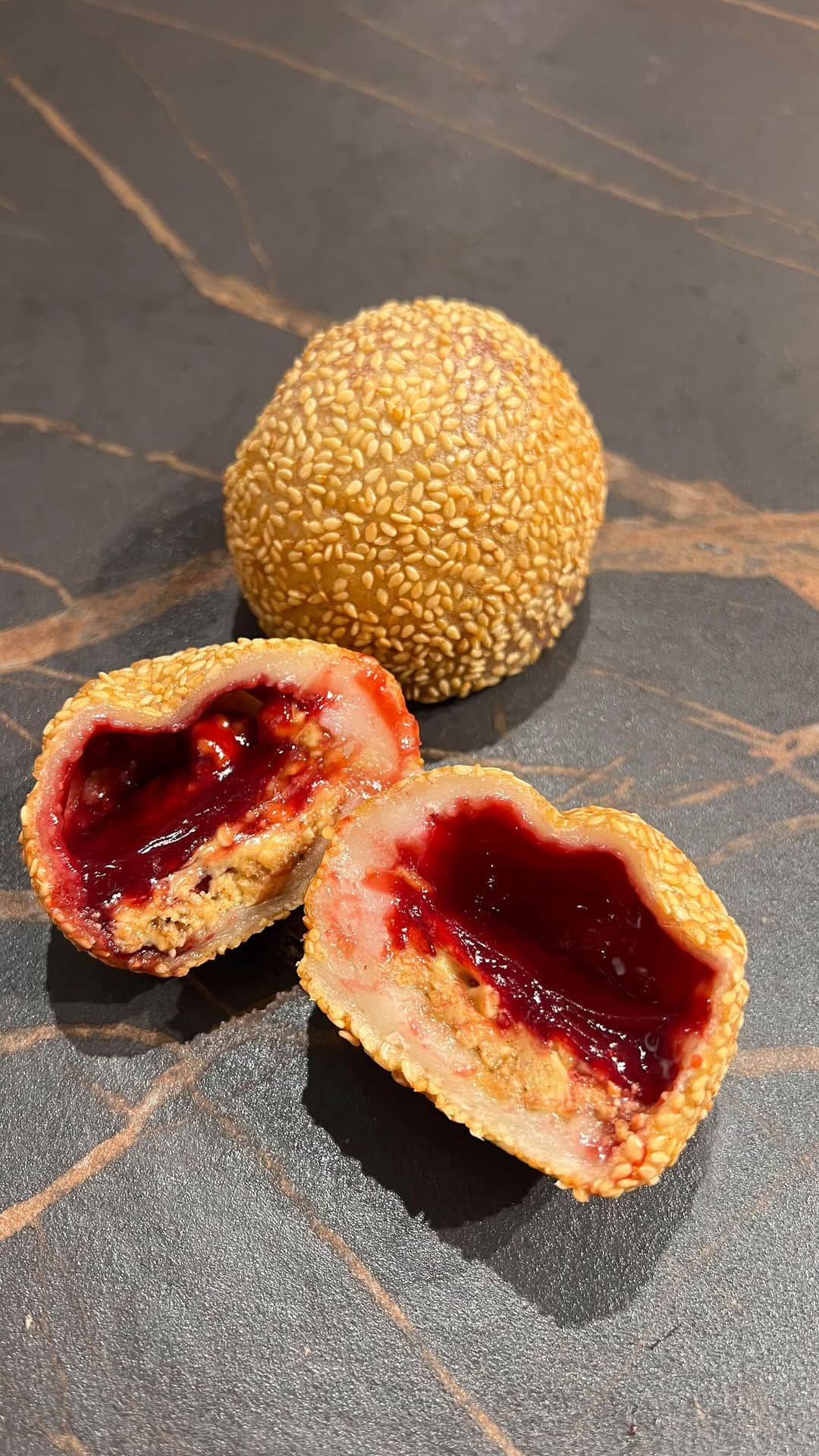DOMINIQUE ANSEL BAKERYのインスタグラム：「Peanut Butter & Jelly Sesame Mochi for our weekend special at @dominiqueanselworkshop. My son Celian loves the classic Chinese sesame mochi (traditionally filled with red bean paste), so I wanted to make a version for him as he heads back-to-school, and that means PB&J! Ours are filled with crunchy peanut butter with a hint of sea salt and homemade raspberry jam, lightly fried until golden. Here in Flatiron today through Sunday only.」