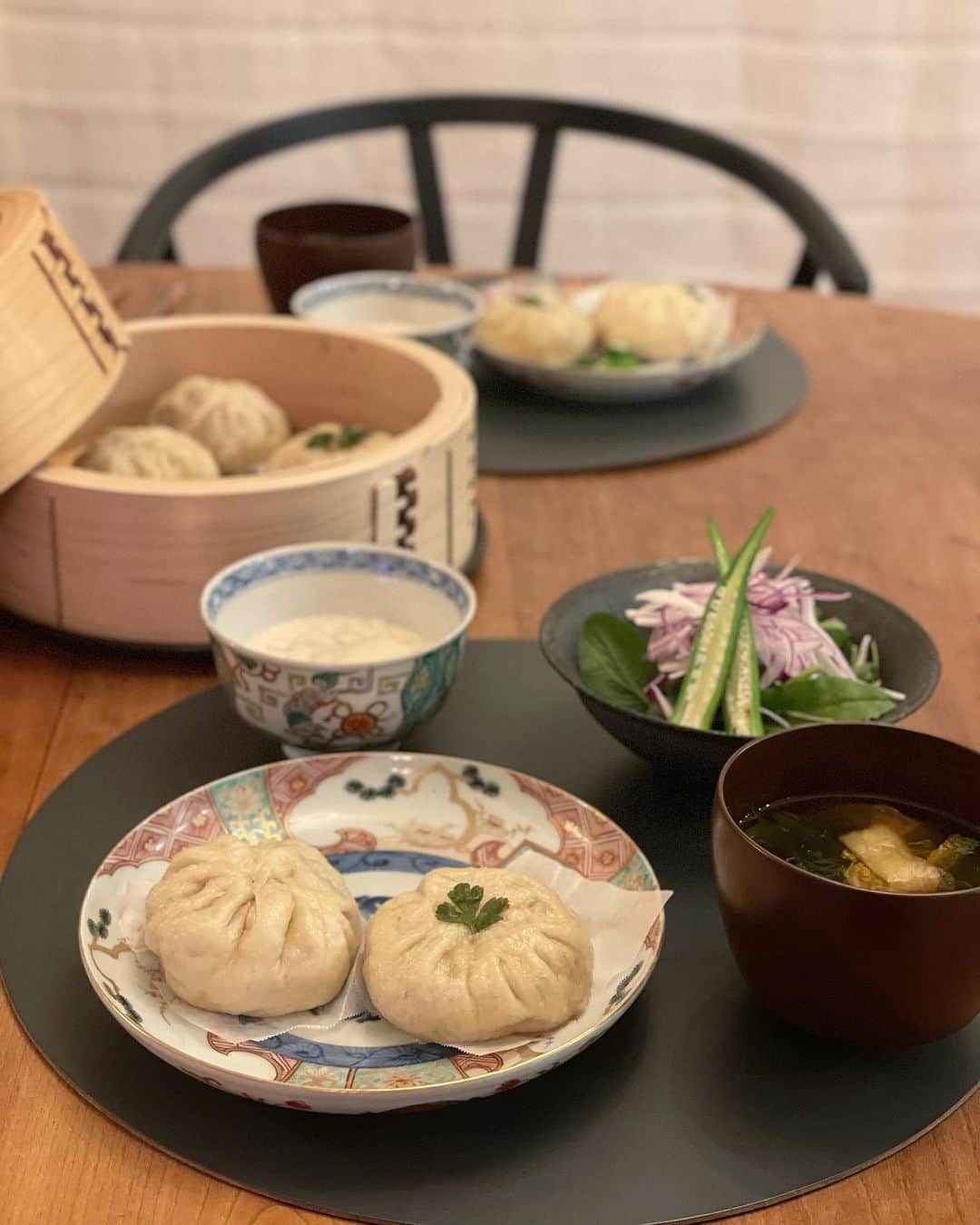 松見早枝子のインスタグラム：「今夜は久しぶりに自家製肉まん。 ・ 花椒が効いたシンプル豚まんに、ちょっと洋風の鶏チーズまん。 ・ ふんわり生地にしたければ二次発酵が必要なのだけど、 自家製酵母の生地なので、二次発酵時間も長くしないと意味がなく、肉だねを入れて35℃に長く置くのも不安なので、二次発酵無しで作っています💨 ・ だから、肉まんというより小籠包寄り。笑 ・ それでも出来たてはやっぱり美味しいです😋 ・ とはいえ、秋冬に向けてもう少しレシピを改良したり、バリエーションを増やしたいなぁ。 これだけ普通にイーストを使ってみようかなぁ。。 とか悩みながら食べたりするから、自分の料理って心から楽しめないのですよね、、😜 ・ 副菜はキムチワカメスープに豆腐花、サラダでした😊 ・ ・ #自家製肉まん #おうちごはん #うちごはん #粮理家 #ウェルネスフードスタイリスト #松見早枝子」