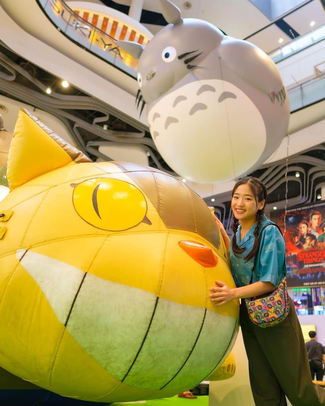仲川遥香のインスタグラム：「Di samping ada Catbus, di atas ada Totoro.. Aku lagi di My Neighbor Totoro kah??!? 🍃🌳  Hehe.. Ini aku lagi di Bugis+, Singapore!! Jadi, kemarin aku habis movie screening film Studio Ghibli, yang juga termasuk rangkaian acara kolaborasi UNIQLO dan Studio Ghibli. Salah satu koleksinya itu ya kemeja dan shoulder bag yang aku pake ini.. Super gemes!! 🎀🪄🌈  Koleksi UT Studio Ghibli ini juga akan launching di Indonesia tanggal 21 Agustus ini, kok. Tenang ajaa! Nanti pas udah launching, langsung beli aja di toko UNIQLO atau UNIQLO.COM karena jujur desain kali ini aku suka banget. Terutama kemeja Totoroku inii 🩵🐼  Nah.. Jadi, di foto ini aku lebih cocok jadi Mei Kusakabe, atau Satsuki Kusakabe?   #GhibliUT @uniqloindonesia」