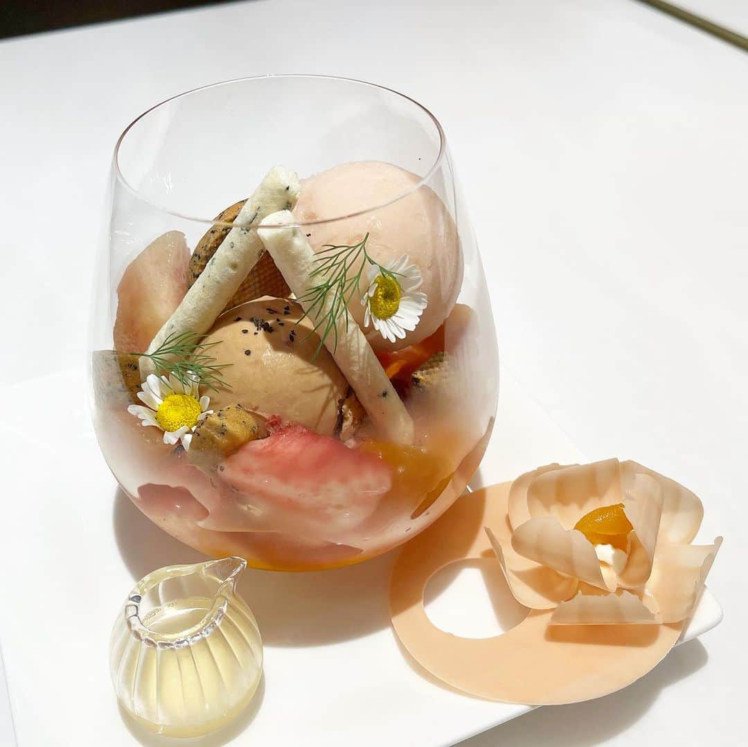 市川歩美さんのインスタグラム写真 - (市川歩美Instagram)「かわいらしいパフェ♡  パスカル・ル・ガック東京で「パルフェフルーリー ペッシュ」をいただきました。  桃のパフェです🍑  ホワイトチョコレートのお花がのったグラスの中には、紅茶のサブレ、シトロンミントのメレンゲ、桃のソルベ、紅茶のアイス、ドライアプリコット、山梨の農園から届いたフレッシュな桃など。  エルダーフラワーの風味や、添えられたディルが爽やかです。  かわいい女の子のような、ラブリーなピーチパフェでした。  このパフェは8月末まで限定、人気のため、事前に予約が必要です。  詳しくは @pascallegac_tokyo  をご確認ください。  #パフェ #桃のパフェ #パスカルルガック東京 #花ひらくパフェ #チョコレート #溜池山王カフェ」8月18日 21時15分 - ayumichocolat