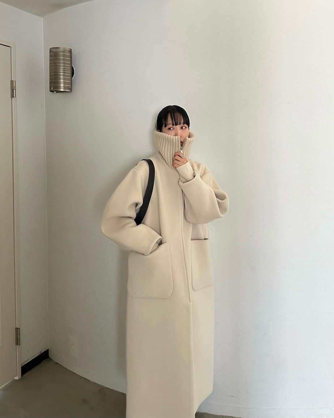 AICOのインスタグラム：「アウター先行予約アイテムのご紹介です。  RIB COLLAR WOOL LONG COAT 着用size1 衿をニットのリブで仕上げたシングルコート。顔周りが隠れるくらいの高い衿が好みなので高めに設定しました。デザインは極力シンプルに構築的なフォルムをデザインしました。高めの衿リブが真冬はマフラー代わりになり、顔まわりが映えながらも防寒性に優れたデザインに仕上げました。リブを立てずにビックカラーとしても着て頂けます。ファスナーは逆開使用になっているので下からもOPEN可能です。 このクリームがかったアイボリーの色も上品で好きです。 素材は日本製の柔らかで滑らかな風合いの膨らみのあるウール素材を仕様しております。 #clane #outer #先行予約会 #clane23awouterpreorder」