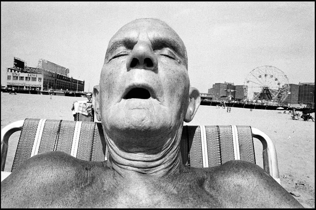 Magnum Photosさんのインスタグラム写真 - (Magnum PhotosInstagram)「Coney Island by @bruce_gilden 🎢⁠ ⁠ In 1969, one year after he first picked up a camera, Gilden took the subway train through Brooklyn to Coney Island to shoot pictures of the sunbathers, the weekenders, the sideshow booths and the Cyclone rollercoaster. ⁠ ⁠ Gilden returned over the next two decades, trudging back and forth along the beach, snapping all manner of eccentric characters. This body of work culminated in the book Coney Island, a humorous and honest view of daily life in Coney Island.⁠ ⁠ On August 31, we are hosting a major library sale at the Magnum Bookshop in London. A wide range of titles will be available, including a special edition of Bruce Gilden's Coney Island, which comes in a slipcase with a signed print (edition of 100) 📚️⁠ ⁠ 🔗 Reserve your spot at the link in bio. ⁠ ⁠ PHOTOS (left to right):⁠ ⁠ (1) Crowds of people clustered together on the beach. Coney Island. NYC. USA. 1977. ⁠ ⁠ (2) Man with plane on boardwalk. Coney Island. NYC. USA. 1976.⁠ ⁠ (3) Old man and muscle man on the beach. Coney Island. NYC. USA. 1976.⁠ ⁠ (4) A family walks along the crowded boardwalk. Coney Island. NYC. USA. 1986. ⁠ ⁠ (5) Man exercising on the beach. Coney Island. NYC. USA. 1977. ⁠ ⁠ (6) A family walks along the boardwalk. Coney Island. NYC. USA. 1986. ⁠ ⁠ (7) Man sleeping with mouth open. Coney Island. NYC. USA. 1977.⁠ ⁠ © @bruce_gilden / Magnum Photos」8月25日 0時01分 - magnumphotos