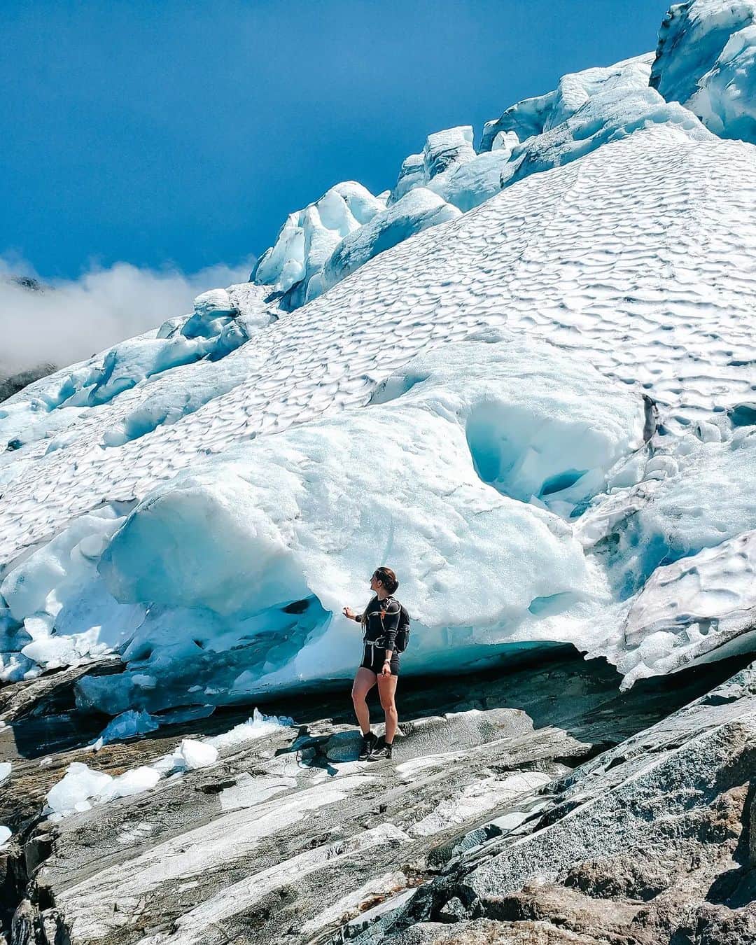 Explore Canadaのインスタグラム：「Gorgeous, gorgeous, glaciers!   Did you know? The dazzling blue hues of certain lakes in British Columbia are a result of nature's paintbrush – rock flour from glacial runoff! As the glacier melts, it carries minuscule rock particles that dance in the water, reflecting sunlight in beautiful blue and green ‘Kool-Aid’ tones. 💙Thanks @tracy_gall for sharing this fun fact!  📷 : @tracy_gall 📍: Pemberton, @HelloBC   #ExploreBC #ExploreCanada   Image description: A person stands on a rocky slope alongside a large glacier with a hand reached out to touch the ice.」