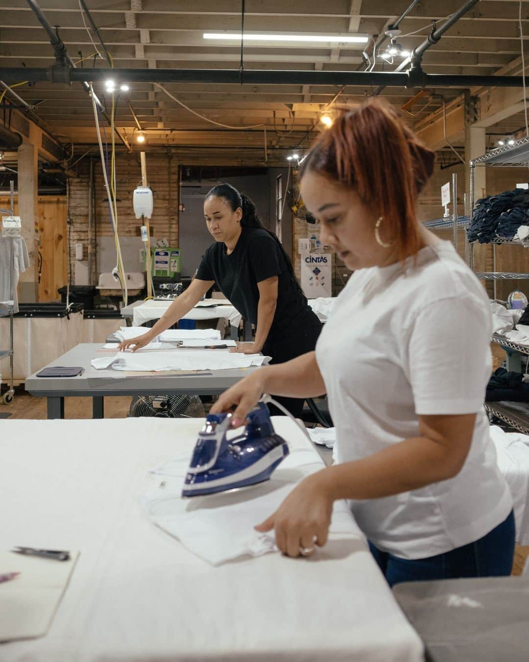 New York Times Fashionさんのインスタグラム写真 - (New York Times FashionInstagram)「Erik Allen Ford and Sasha Koehn started the label Buck Mason with a lofty goal: to make a superior T-shirt. They recently bought a sewing factory and cloth mill in Mohnton, Pennsylvania, where the brand now manufactures some of its most popular styles.  Over the past decade, the brand has grown to sell almost a dozen different short-sleeve T-shirts, along with other basics like jeans, sweatshirts and button-up shirts. Buck Mason touts its domestic manufacturing on its website, labeling some products as made in the U.S. and others as made with materials fabricated or grown in the country.  The founders had been looking into building a new factory in Texas, Ford said, when he got a call from a friend about the factory in Mohnton and its associated mill in neighboring Shillington. Both sites had been in and out of operation since they were opened in 1878 and in 1906.  Now they are owned by Buck Mason. At the factory, some employees are responsible for cutting and sewing T-shirts, while others iron them by hand or package them for shipping. About 10,000 T-shirts are made there a month, Ford said. “By fall, we aim to double the capacity,” he added. “The goal is to quadruple it.”  Take a look inside the Pennsylvania factory where @buckmason makes T-shirts at the link in our bio. Photos by @whereismyphd」8月29日 4時05分 - nytstyle