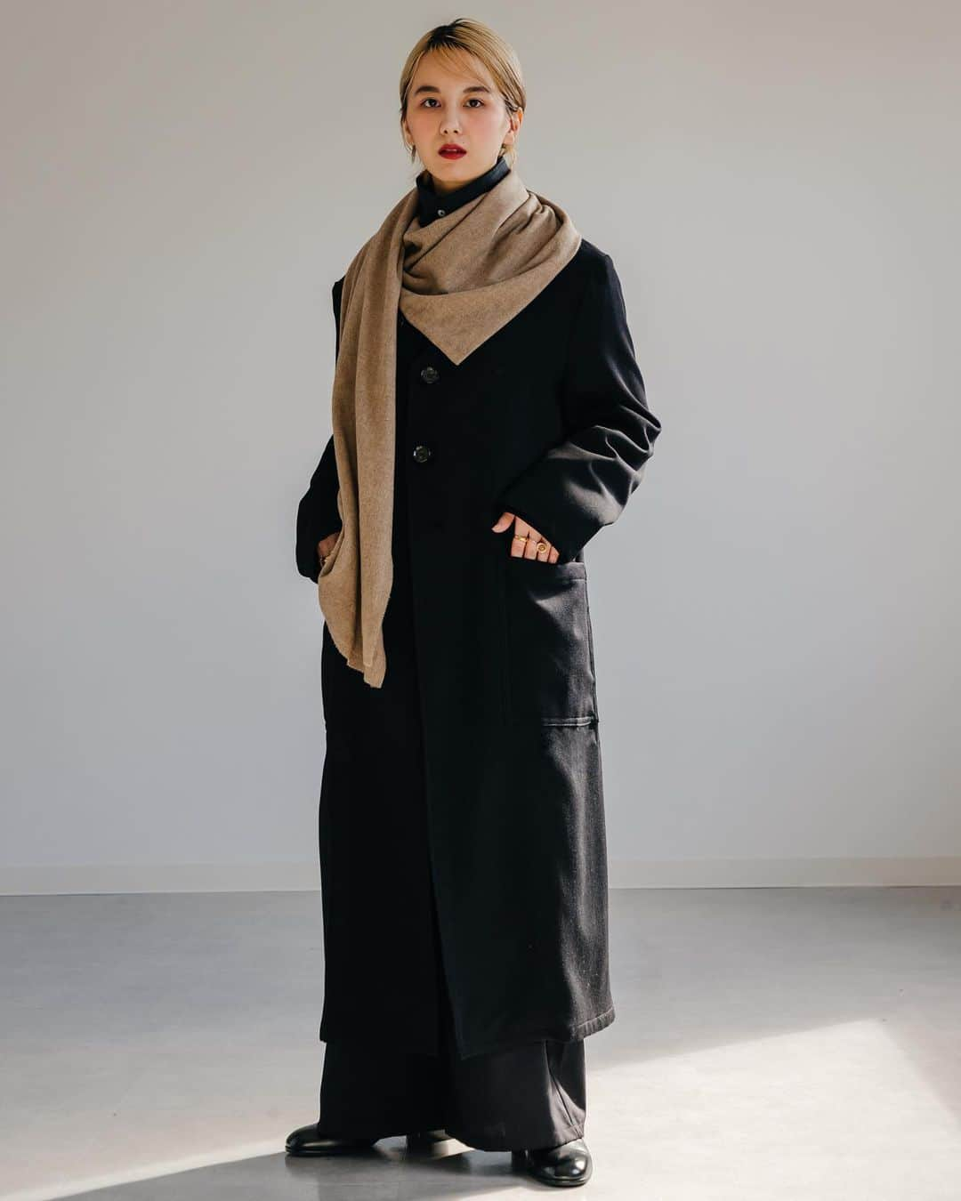 ノアファーのインスタグラム：「23AW Detachable cashmere stole coat ボタンで取り外し可能なカシミヤストールの付いたウールギャバジンノーカラーコート。春秋の暖かい時期はノーカラーコートとして着用し、寒くなってきたらストールを取り付けて着用する2wayデザインなので、春秋冬と長いシーズン活躍してくれる1着。 巻き方も様々なアレンジが可能なので、自分だけの巻き方を見つけて楽しんで欲しい。 ブラック×ブラックでは無く、ブラック×ベージュにしたのが今シーズンらしくもあり上質な雰囲気が漂う。  #noirfr #23aw」