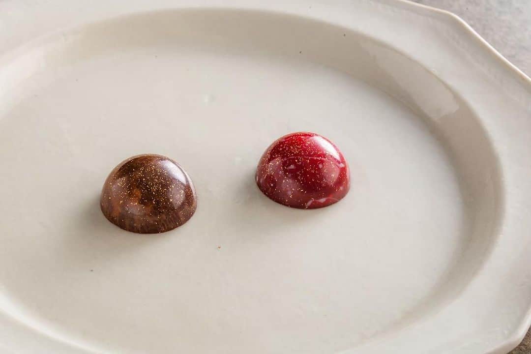 Decadence du Chocolatのインスタグラム：「《BEAUTY》  BEAUTYをテーマに考案した限定ボンボン「ローズ」「デーツ」の2種類をご紹介します！  艶々と赤く光るボンボンショコラは美容に良いとされるザクロ、リラックス効果があるローズを掛け合わせています。 ローズの優しい香りとザクロの甘酸っぱい風味が口の中で広がるこだわりの商品です。  半球型ダークカラーのボンボンショコラは、アジアや中東を起源とするスーパーフード、デーツと黒糖の意外な組み合わせ。 口に繊維質が残るデーツを、ショコラティエはカカオ40%前後の黒糖チョコと組み合わせる事で、優しい余韻に変化させる事を実現させました。 コーティングはダークチョコレートなので、後味はしっかりとカカオを感じられます。  ローズとデーツの限定フレーバーは女性に優しい効果がたっぷり。 キレイになりたい気持ちに寄り添い、ショコラで癒しの時間を格上げします✨  #beauty  #decadanceduchocolat  #デカダンスドュショコラ」