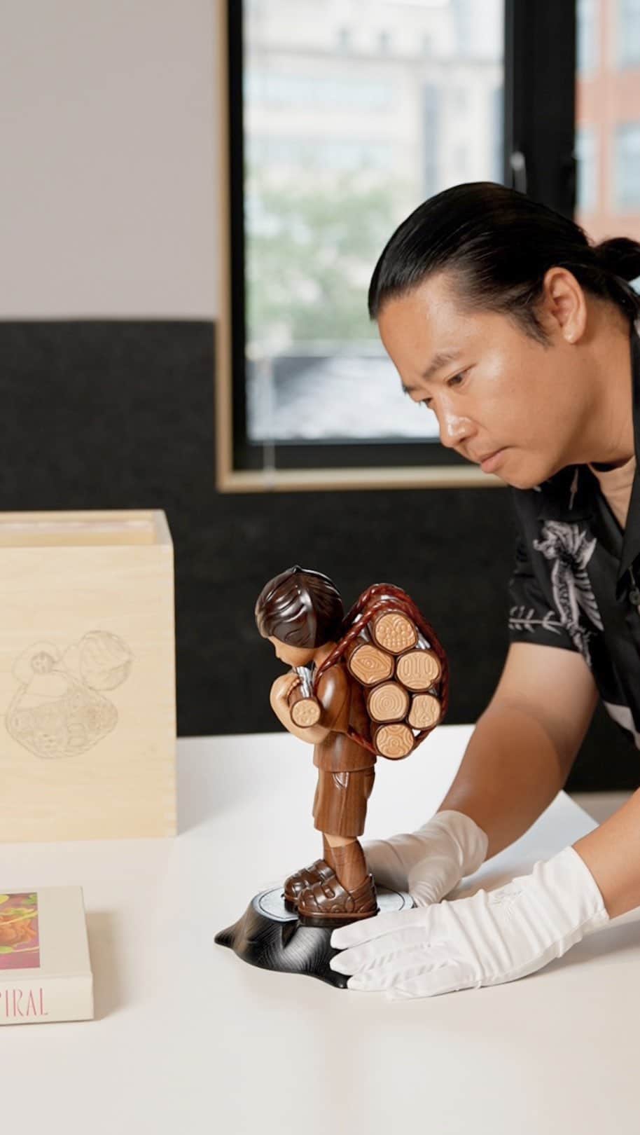 ジェームス・ジーンのインスタグラム：「Woodcutter 木, 30cm, releases today, August 30 with @galleryallart   An edition of 35+5APs, 木 is a character that means wood, as the material of this sculpture expresses the story of the Woodcutter both physically and spiritually. These pieces are exquisitely sculpted and stained, and the warmth of the character radiates from the natural material.  And yes, I know it’s shocking that I’m not wearing a black t shirt. These are the sacrifices I make when filming an unboxing video.   DM @galleryallart for more info」