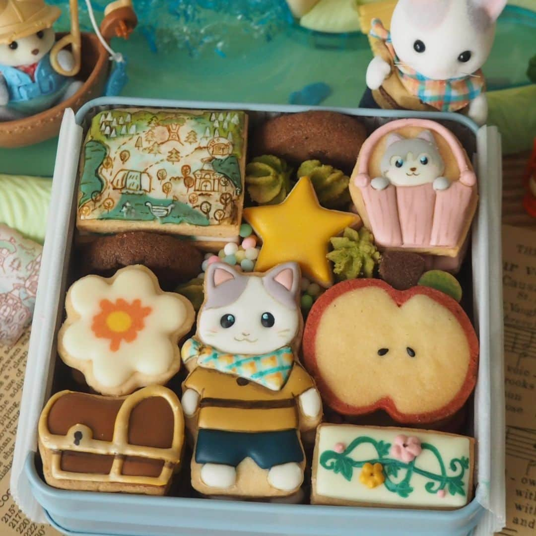 上岡麻美のインスタグラム：「シルバニアファミリークッキー缶🌼  シルバニアファミリー　@sylvanianfamilies_jp 新商品の ・どきどき探検セット ・ひみつの森の大きな滝 をイメージしてクッキー缶を作りました🥰✨ 探検セットでは探検服を着たラテ猫きょうだいのセットになっていて可愛くて🌼ラテ猫押しです😁 地図を真似てアイシングにしてみました☺️❤️ ひみつの森の大きな滝は、バケツのリフトやつたのロープウェイ、ツリーハウスなどのがあり見てるだけで楽しくなっちゃいます✨✨宝箱があり、鍵も隠せたりと仕掛けも楽しいのでぜひ遊んでみてくださいね😁  #シルバニアファミリー#シルバニアファミリーの赤ちゃん #シルバニア公式アンバサダー#sylvanianfamilies #クッキー缶#アイシングクッキー#アイスボックスクッキー#cookies#iceboxcookies#icingcookies#sweets#お菓子作り」