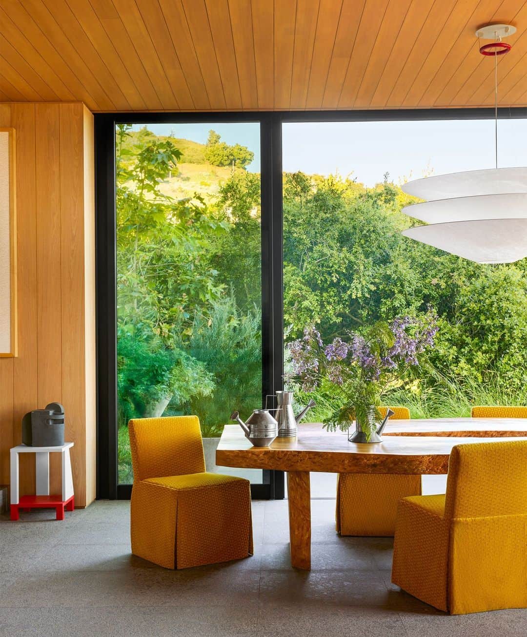 ELLE DECORのインスタグラム：「Alfresco dining goes indoors, thanks to the lush floor-to-ceiling views in a California home designed by Jamie Bush (@jamiebushco). The inspiration? Leo Marx’s 1964 book “The Machine in the Garden,” which critiqued  industrialization’s mark on the natural world and remains a favorite in architecture programs. “We thought about the romanticized aesthetic of the man-made within a bucolic setting,” Bush says. Here, a set of vintage swivel chairs surrounds a Balinese bleached hardwood table. The pendant is by Ingo Maurer.  To see the rest of this arresting residence, as toured in our September 2023 Style Issue, click the link in bio. Written by @cokhio. Photographed by @yosihiromakino. Styled by @tessawatson.」