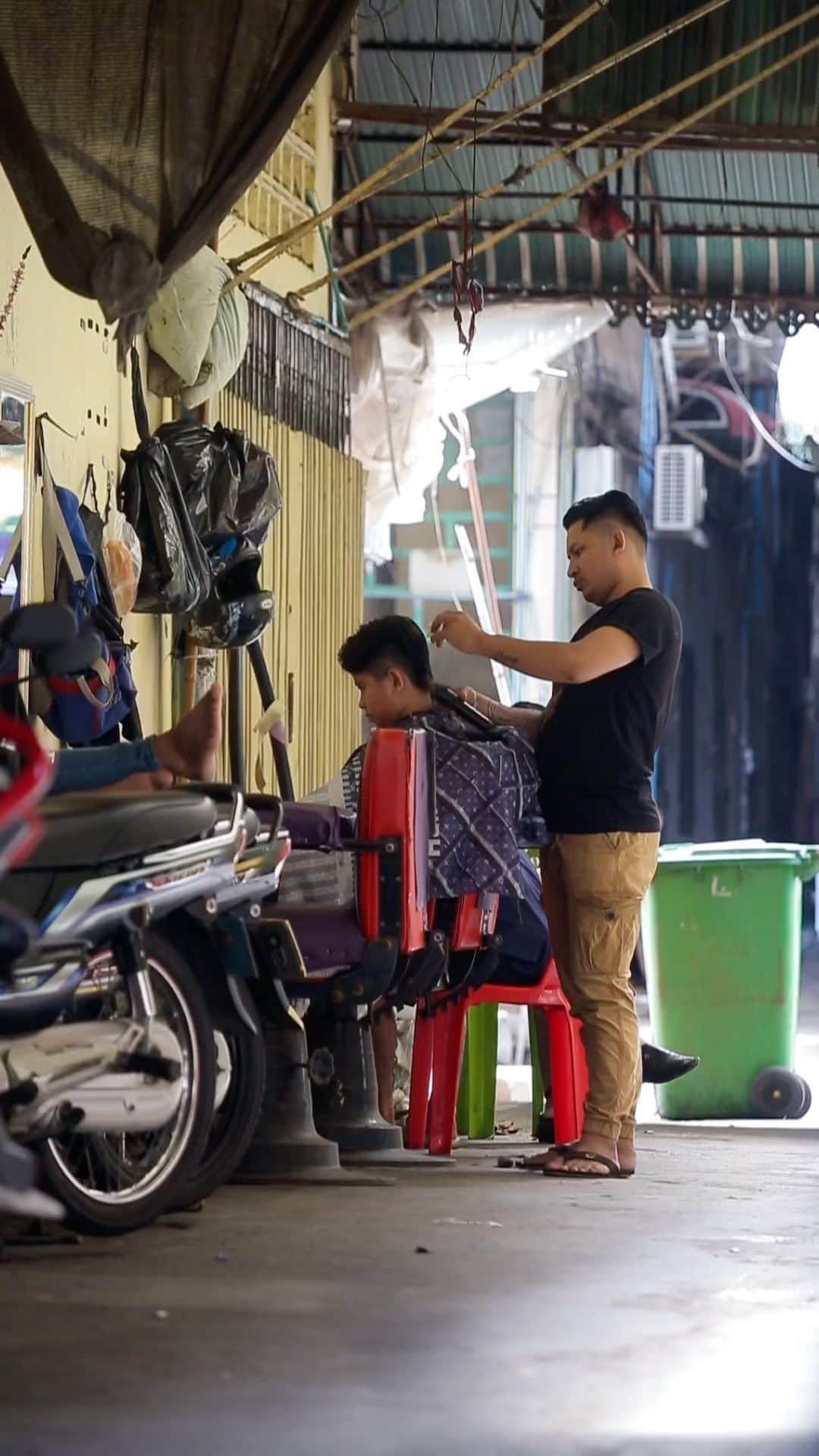 Shunsuke Miyatakeのインスタグラム：「A barber on the street of Phnom Penh /   It is almost impossible to see these street barbers on the street any more in Japan, but there are still many street barbers in Phnom Penh. Some go before working, others go before dinner with friends. From morning till late, we can see them at several places. Here is the street just one street south from the Orussey Market. I just wanted to document this everyday life scene which might vanish sooner or later as a community memory.   ---  プノンペンの路上理髪店　  日本ではほとんど見かけなくなった路上理髪店だが、プノンペンにはまだたくさんある。出勤前に行く人もいれば、友人との夕食前に行く人もいる。朝から晩まで、あちこちで見かける。こちらはオルセーマーケットから1本南の通り。いずれ消えてしまうかもしれないこの日常風景を、地域の思い出として記録しておきたかった。  . . . . #phnompenh #cambodia #cambodia🇰🇭 #cambodiatrip #cambodiatravel #cambodiatourism #phnompenhlife #phnompenh #phnompenhreels #reelvideo #reelinstagram #socialdocumentary #socialdocumentaryphotography #documentaryphotography #storyofthestreet #PhnomPenhPhotographyCollective」